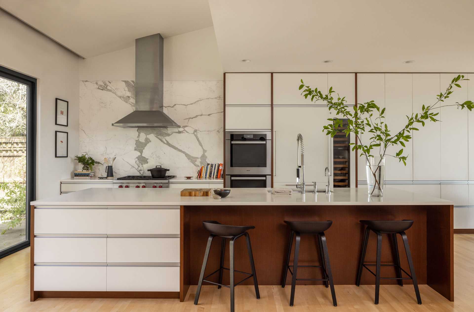 This new bright and open kitchen includes minimalist white cabinets with wood accents.