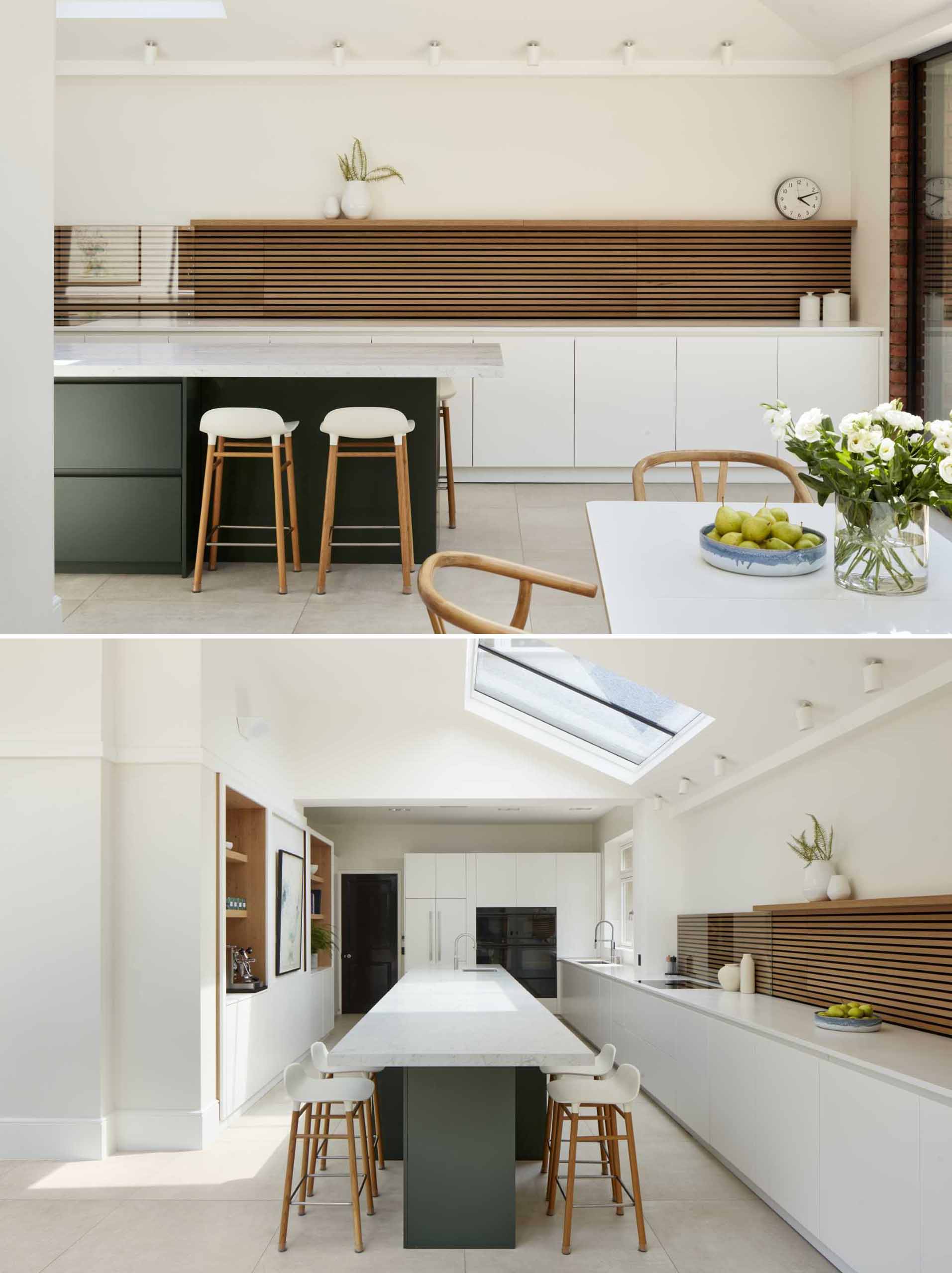 A modern kitchen with a large island, black and white cabinetry, and wood slat accent.