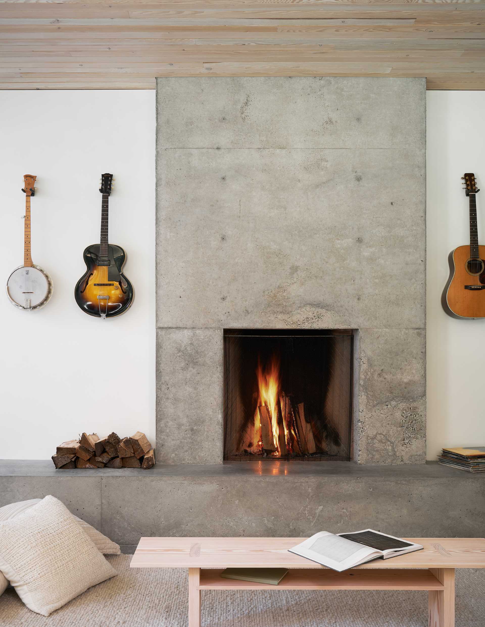 In this modern living room, the concrete hearth of the fireplace lines the wall and transitions into a bench with a skylight above.