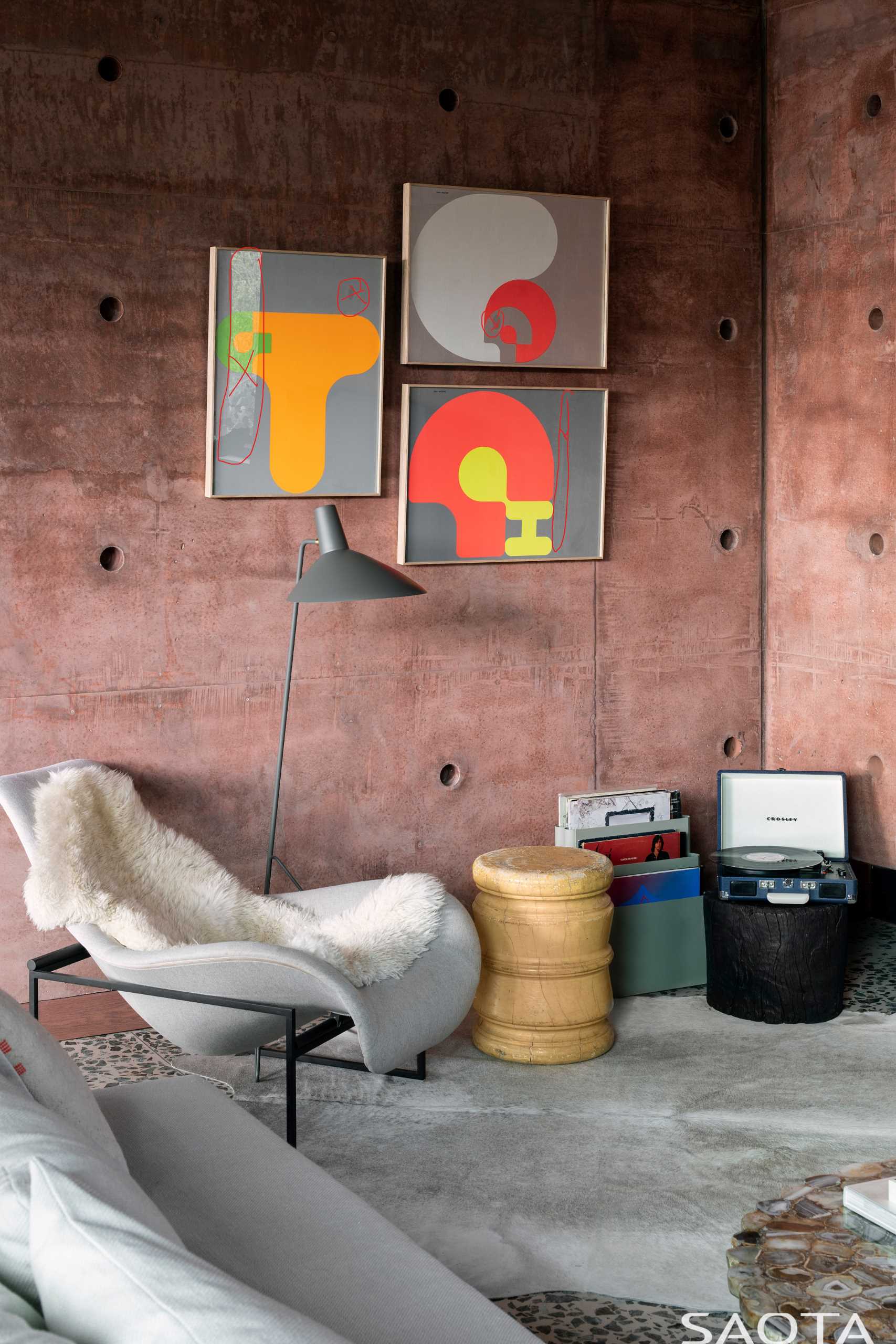 A TV room showcases red-pigmented concrete walls and an L-shaped couch.