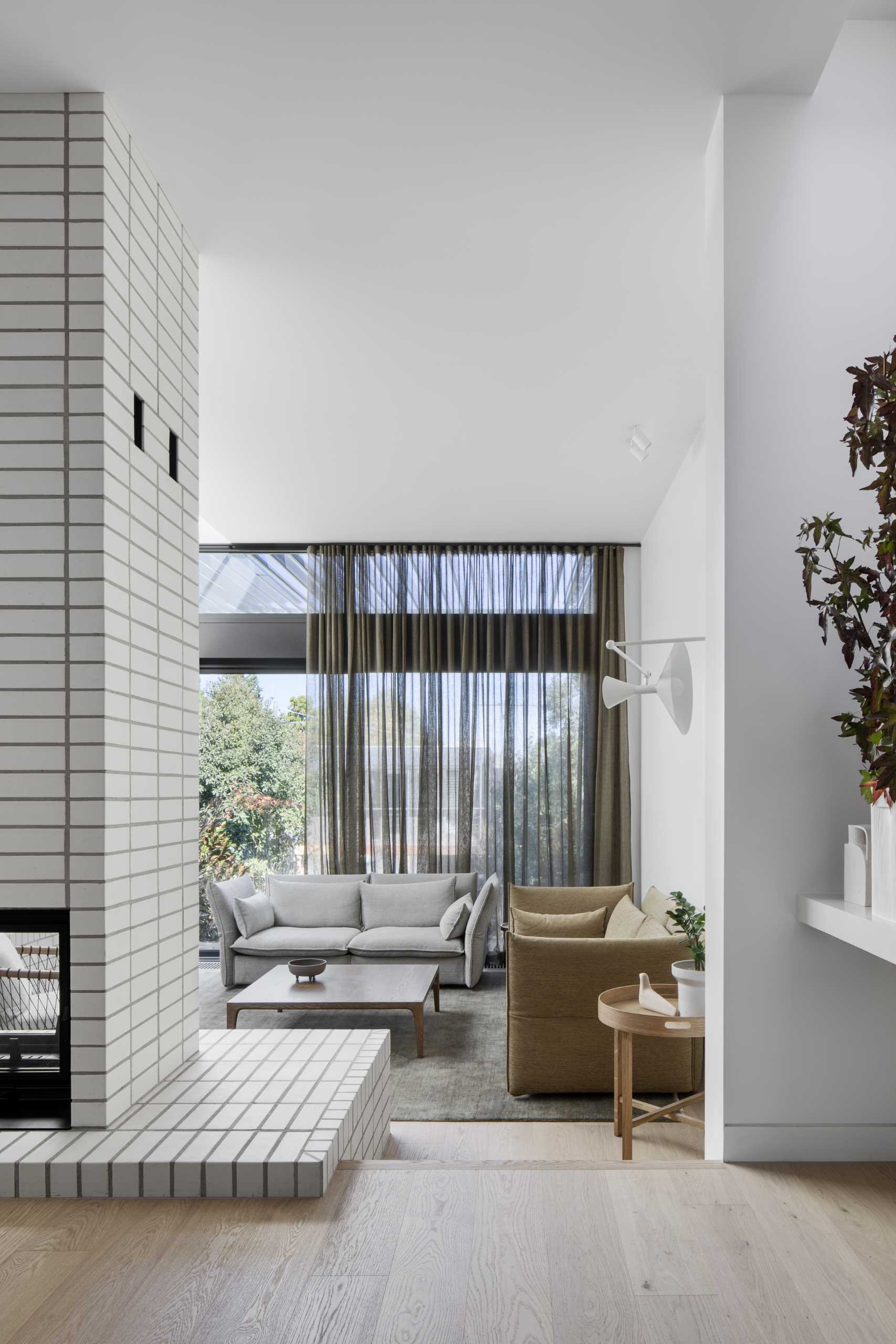 The living room, at the rear of the home, is sunken down from the kitchen and dining area, and features wood shelving and stacked white bricks.