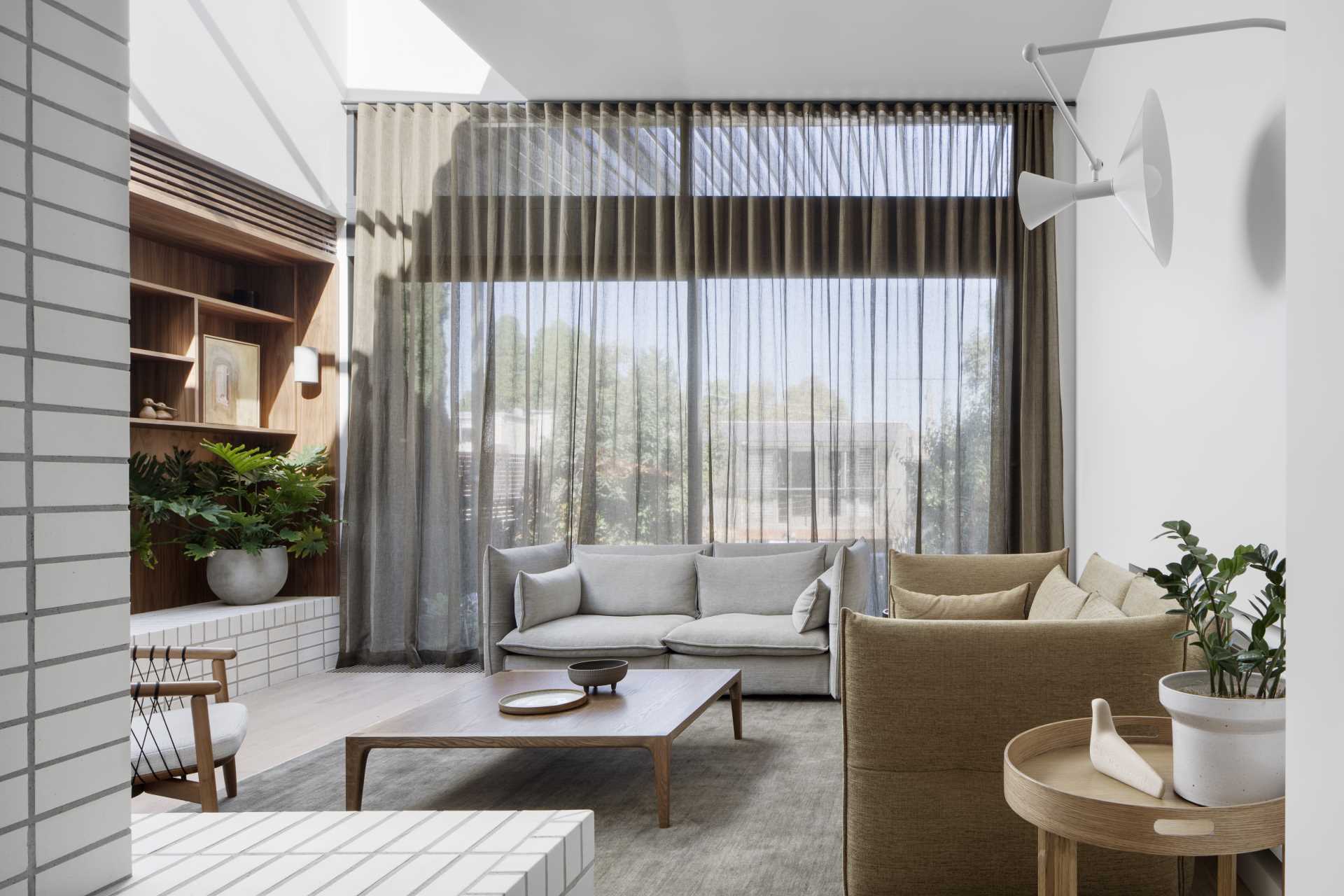 The living room, at the rear of the home, is sunken down from the kitchen and dining area, and features wood shelving and stacked white bricks.