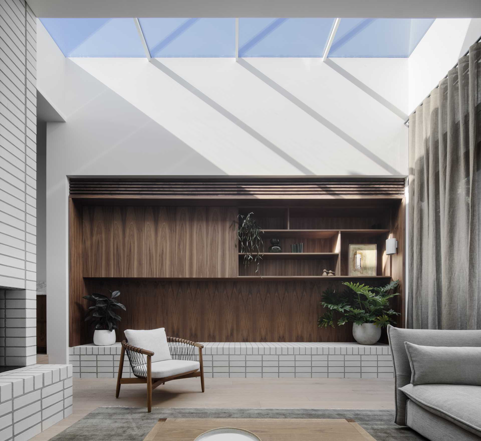 The living room, at the rear of the home, is sunken down from the kitchen and dining area, and features wood shelving and stacked white bricks.