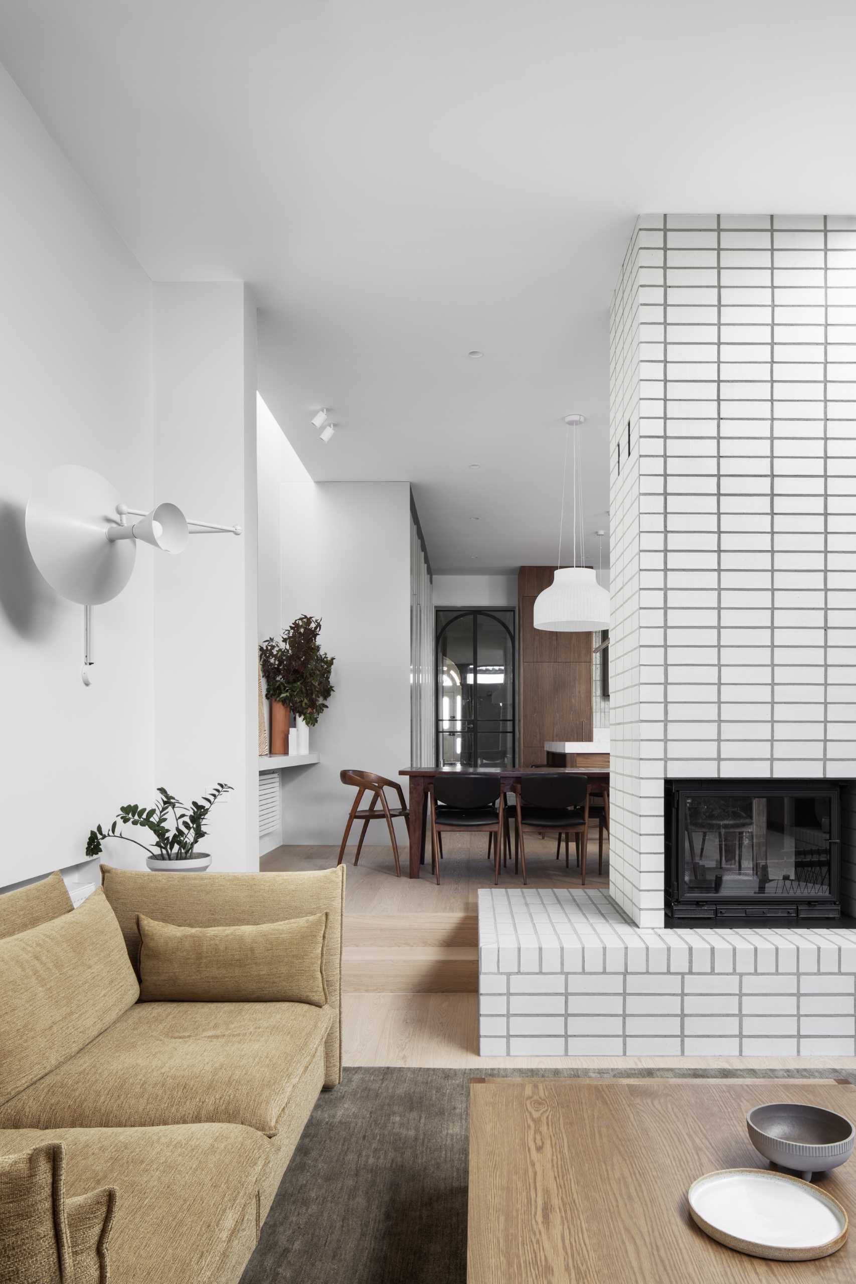 The living room, at the rear of the home, is sunken down from the kitchen and dining area, and features wood shelving and stacked white bricks.