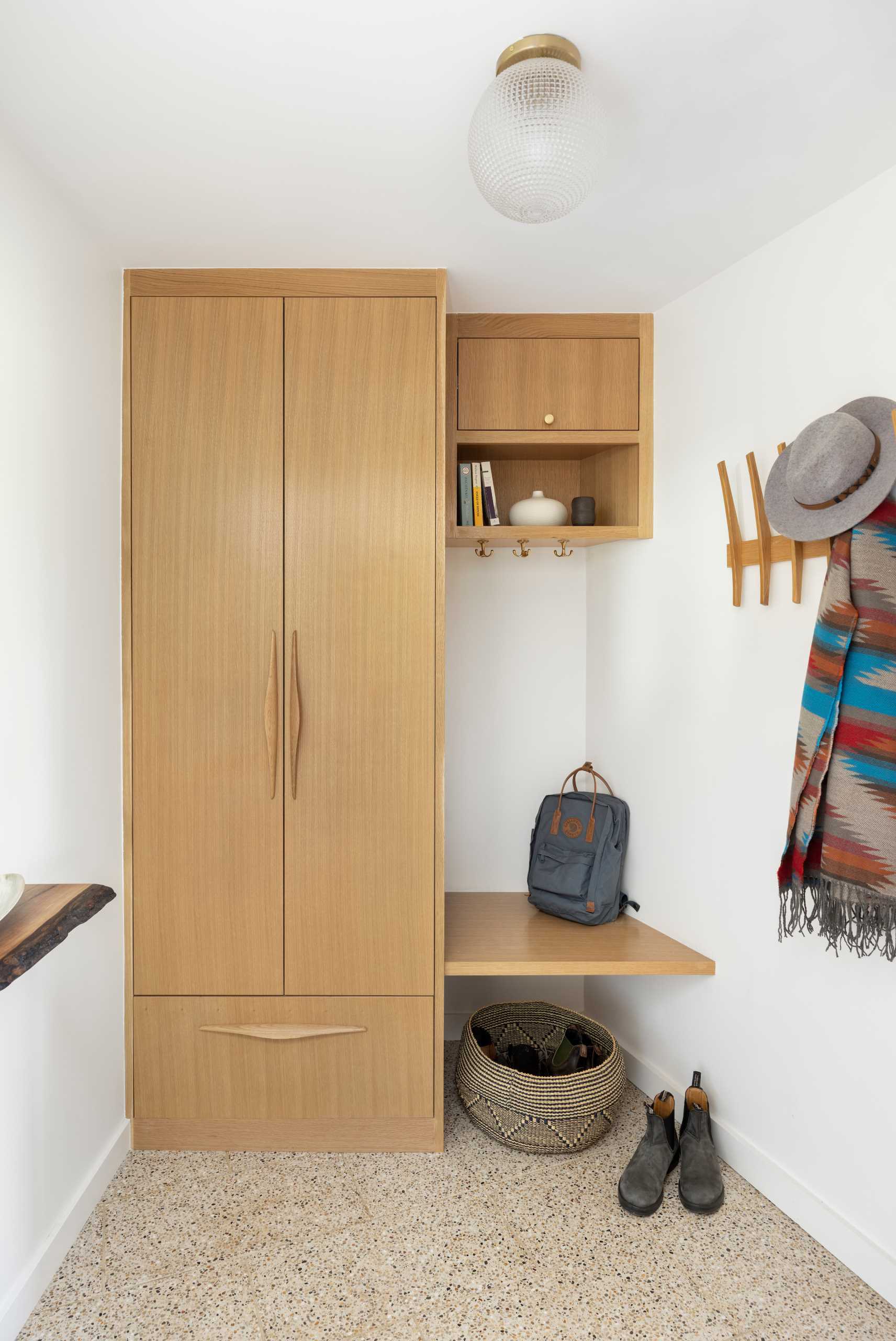 A small mudroom includes a built-in cabinet and drawer, and a small floating wood bench.