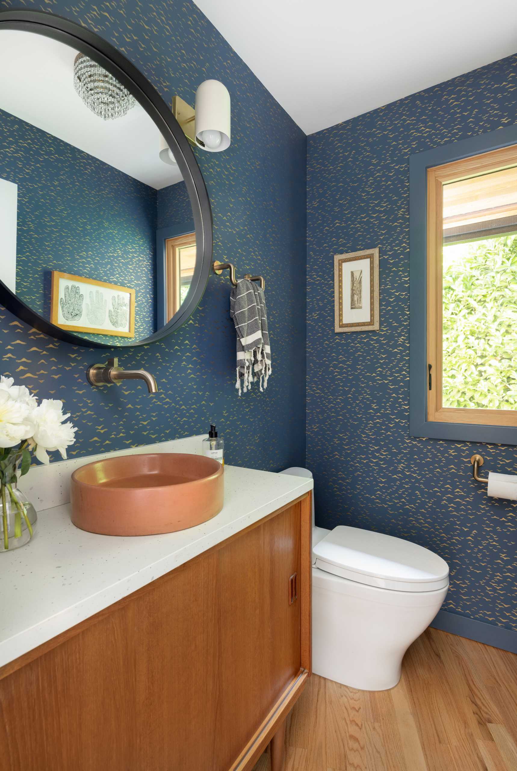 The updated powder room includes wallpapered walls with delicate metallic accents.
