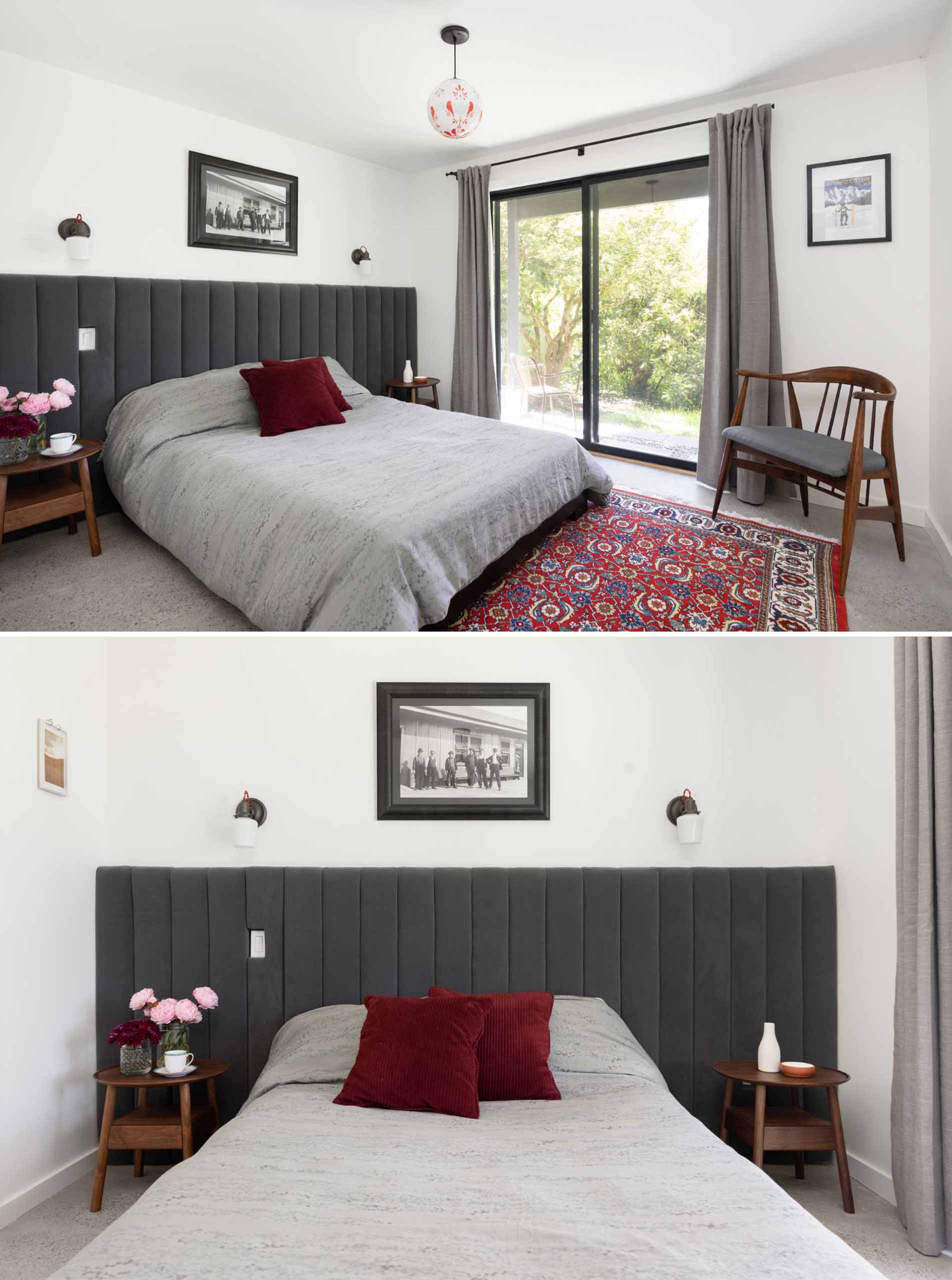 A modern bedroom with a dark grey upholstered headboard and a sliding door that opens to the outdoors.