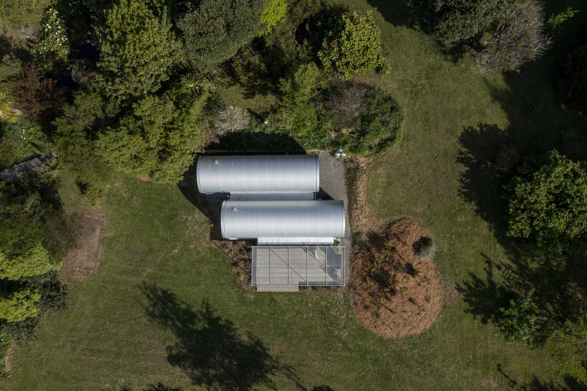 A modern and small one-bedroom home with a study, kitchen, loft, and curved roof.