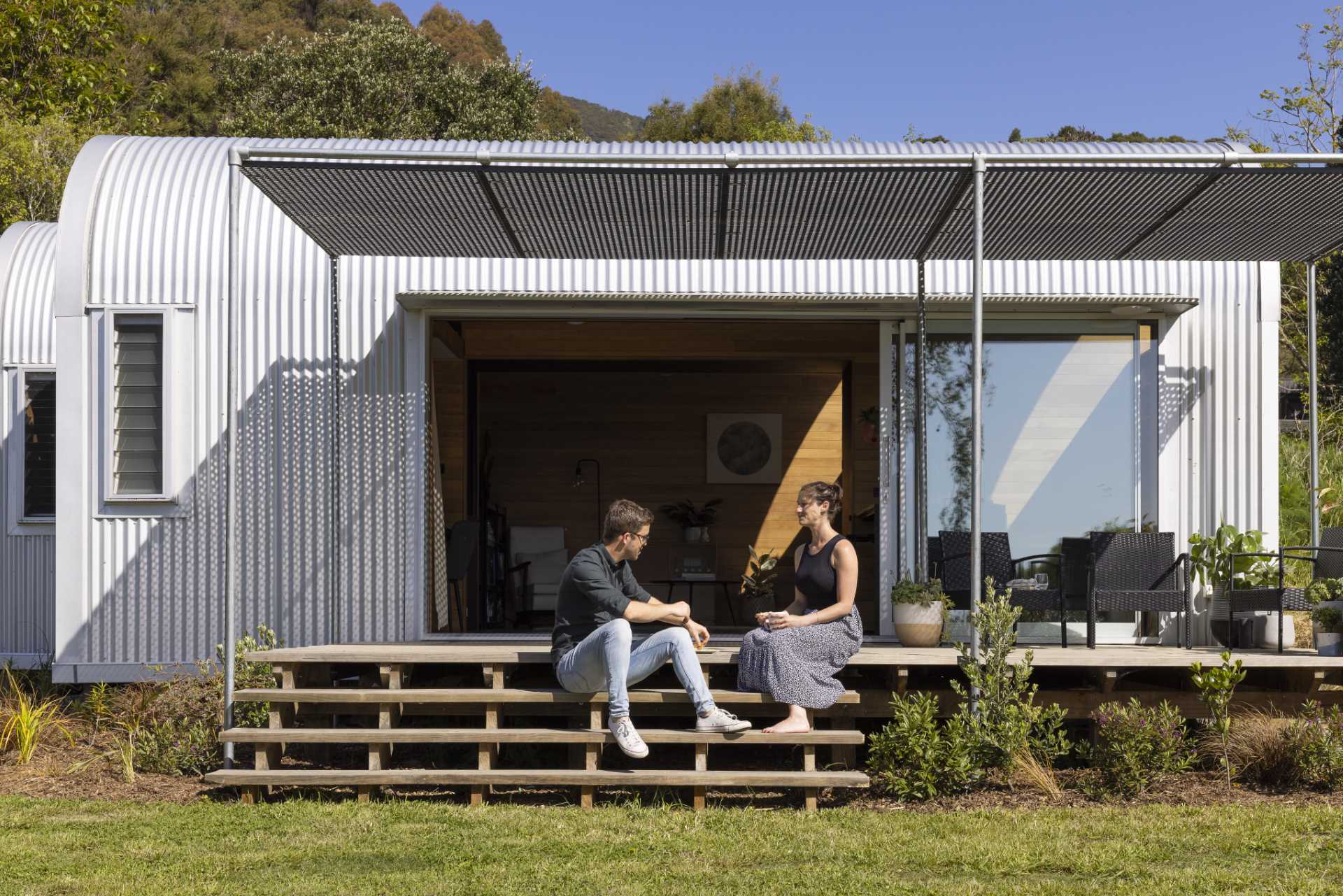 A modern and small one-bedroom home with a study, kitchen, loft, arched windows, and curved roof.