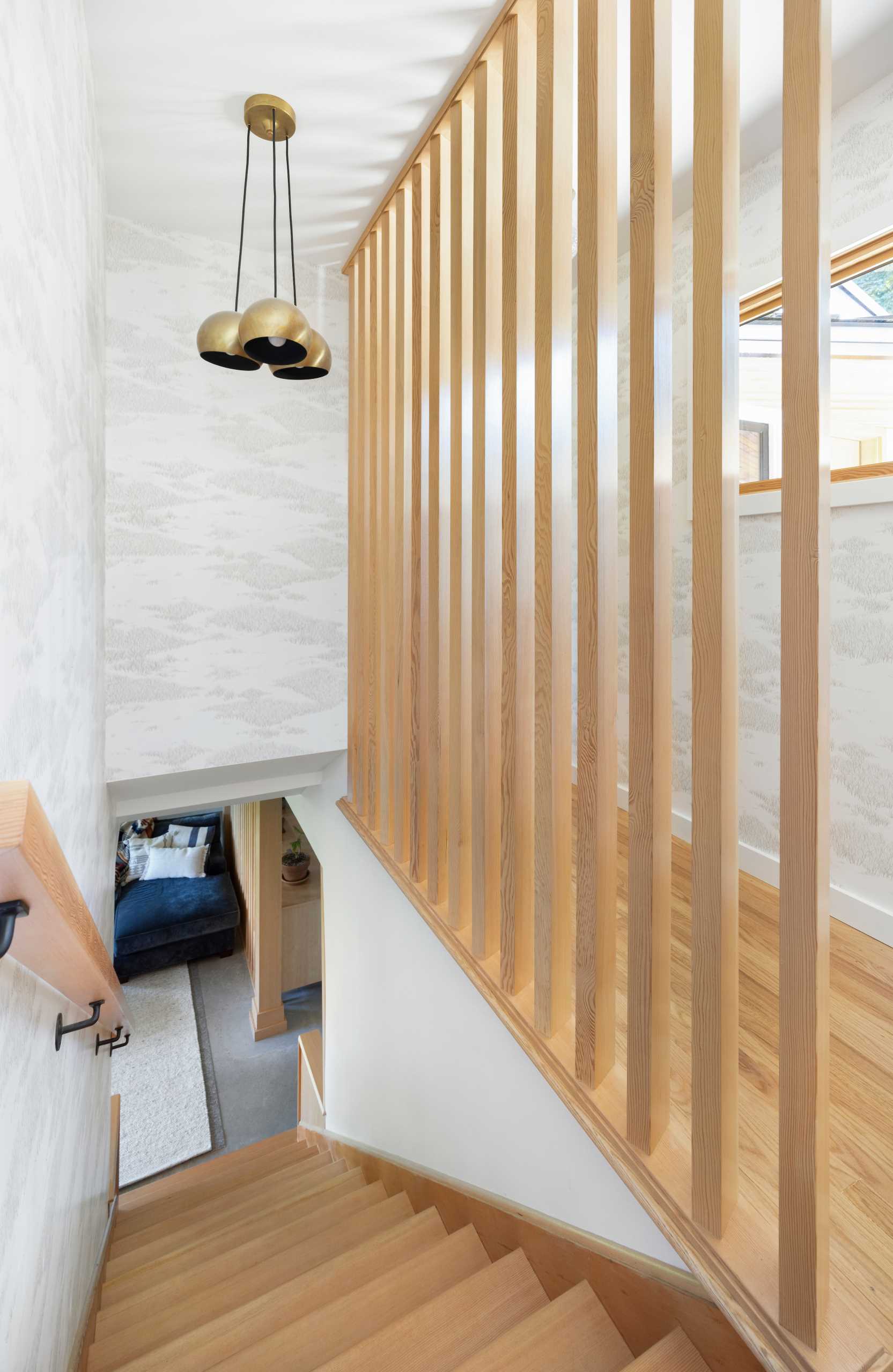 This updated hallway includes vertical wood slats that serve as dividers not only to the downstairs stairwell but also in the family room itself.