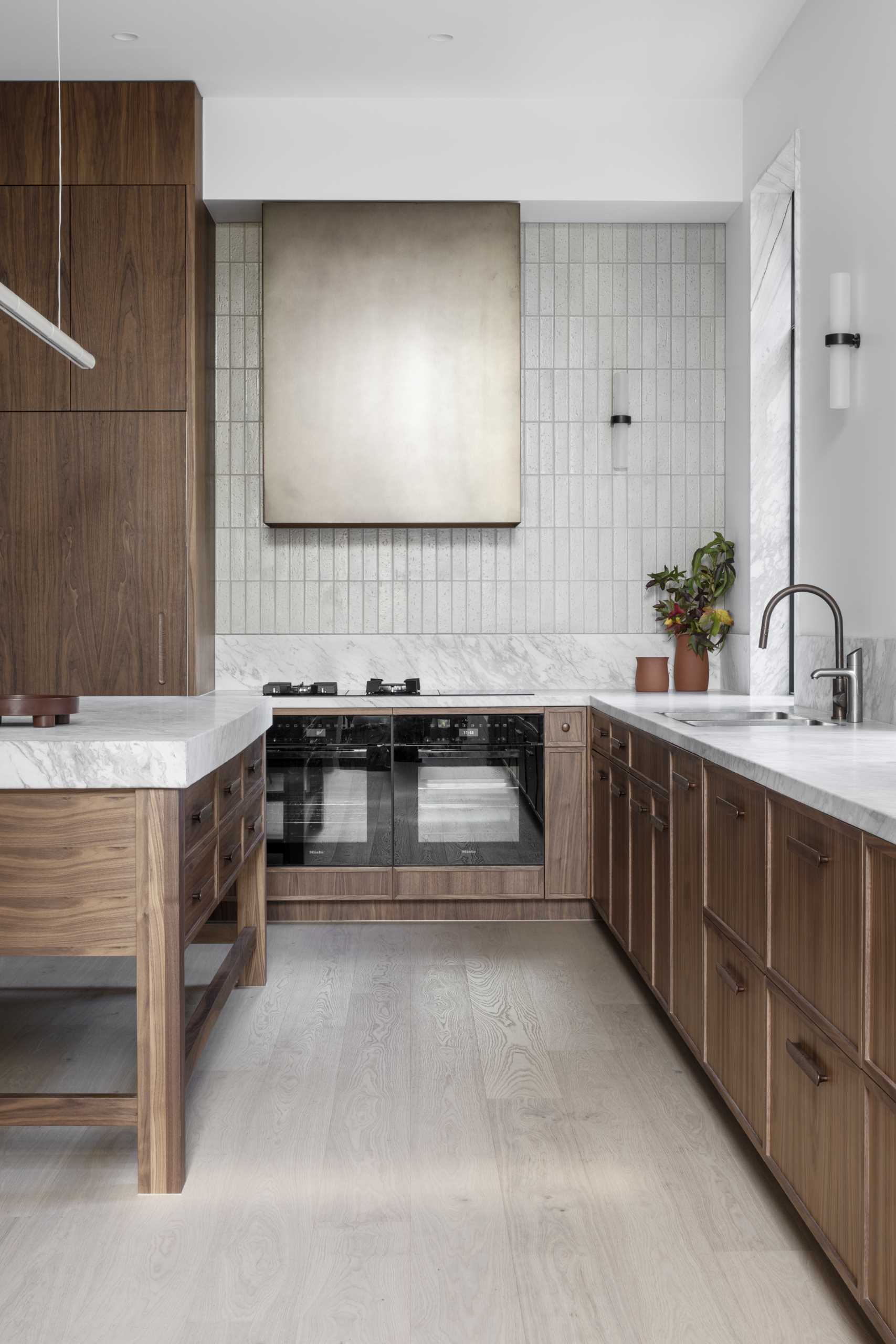 A modern kitchen with natural walnut veneer joinery and black steel-framed windows and doors.