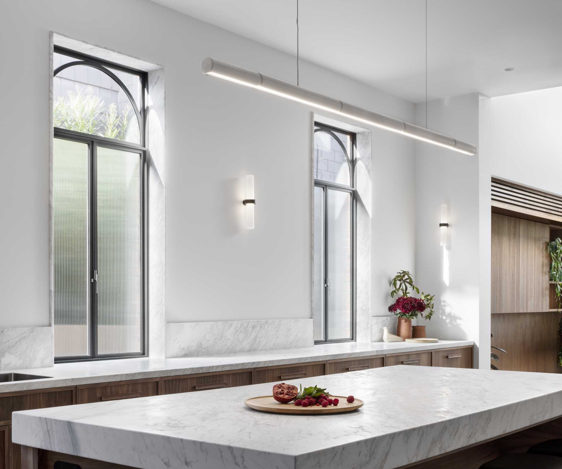 A modern kitchen with natural walnut veneer joinery and black steel-framed windows and doors.