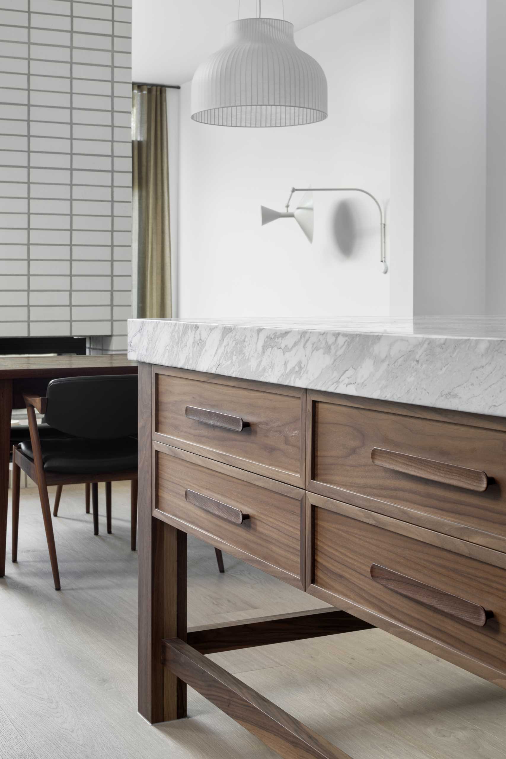 A modern kitchen with natural walnut veneer joinery and black steel-framed windows and doors.