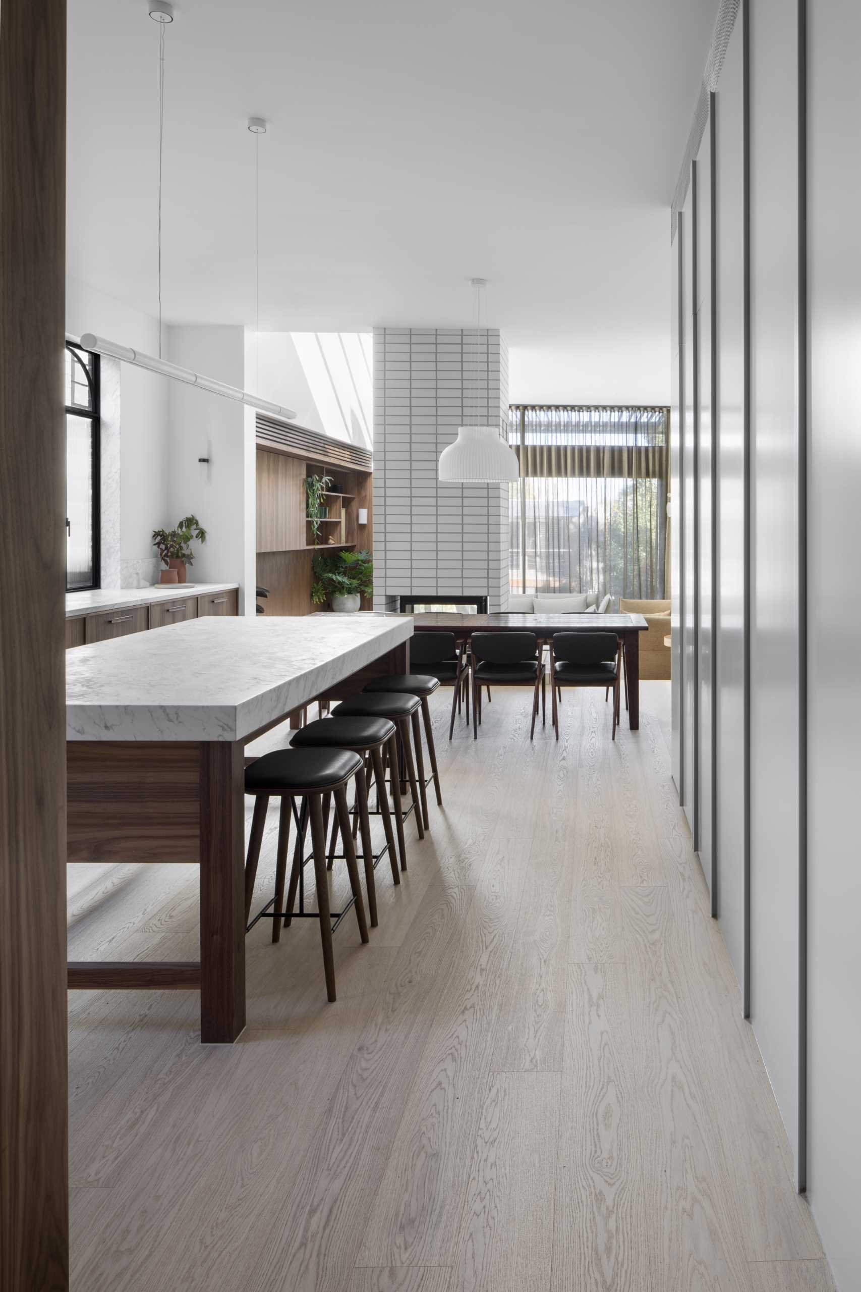 Separating the kitchen from the living room is the open-plan dining area and double-sided wood fireplace with white stacked brickwork.