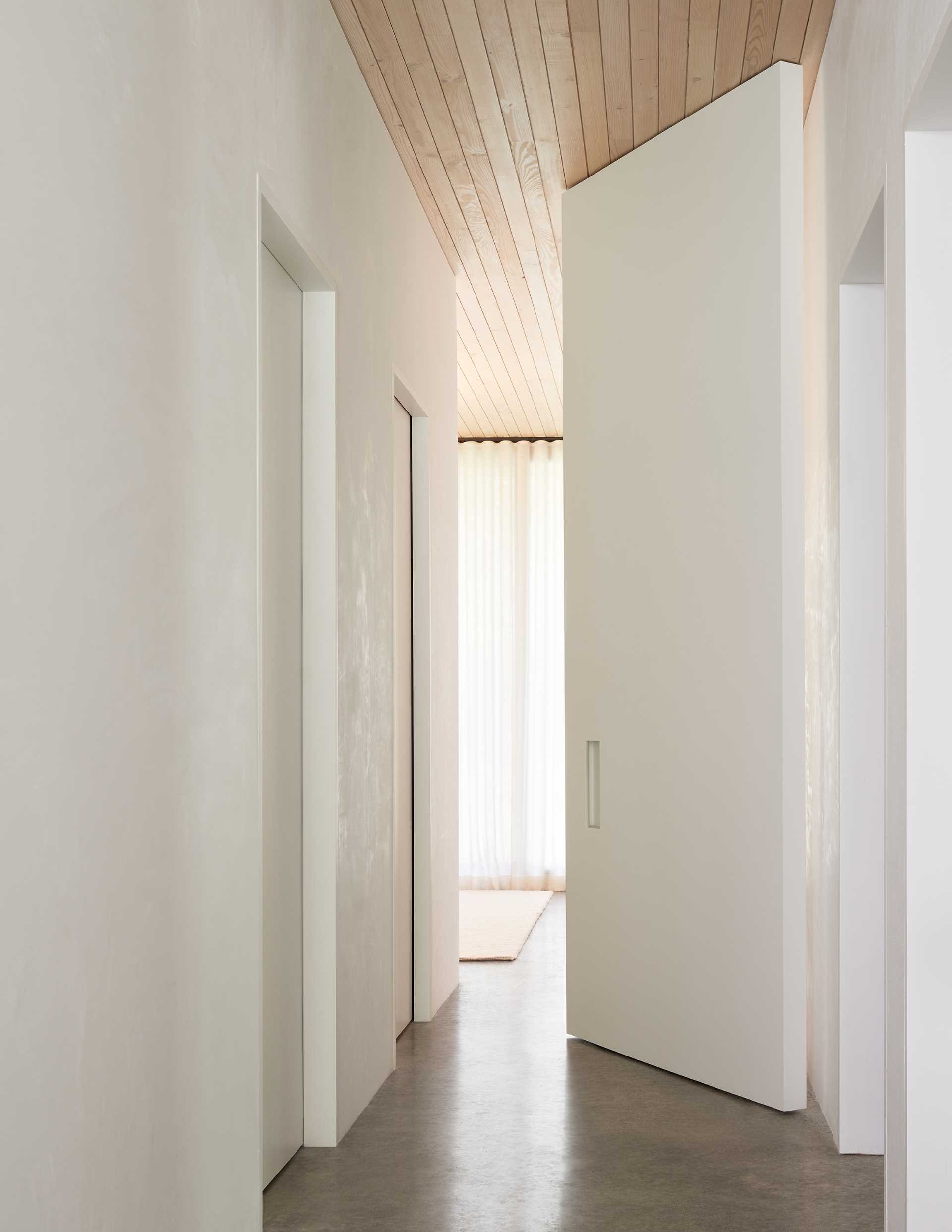 The primary bedroom, located at the end of the hallway, is hidden behind a custom floor-to-ceiling pivoting door.