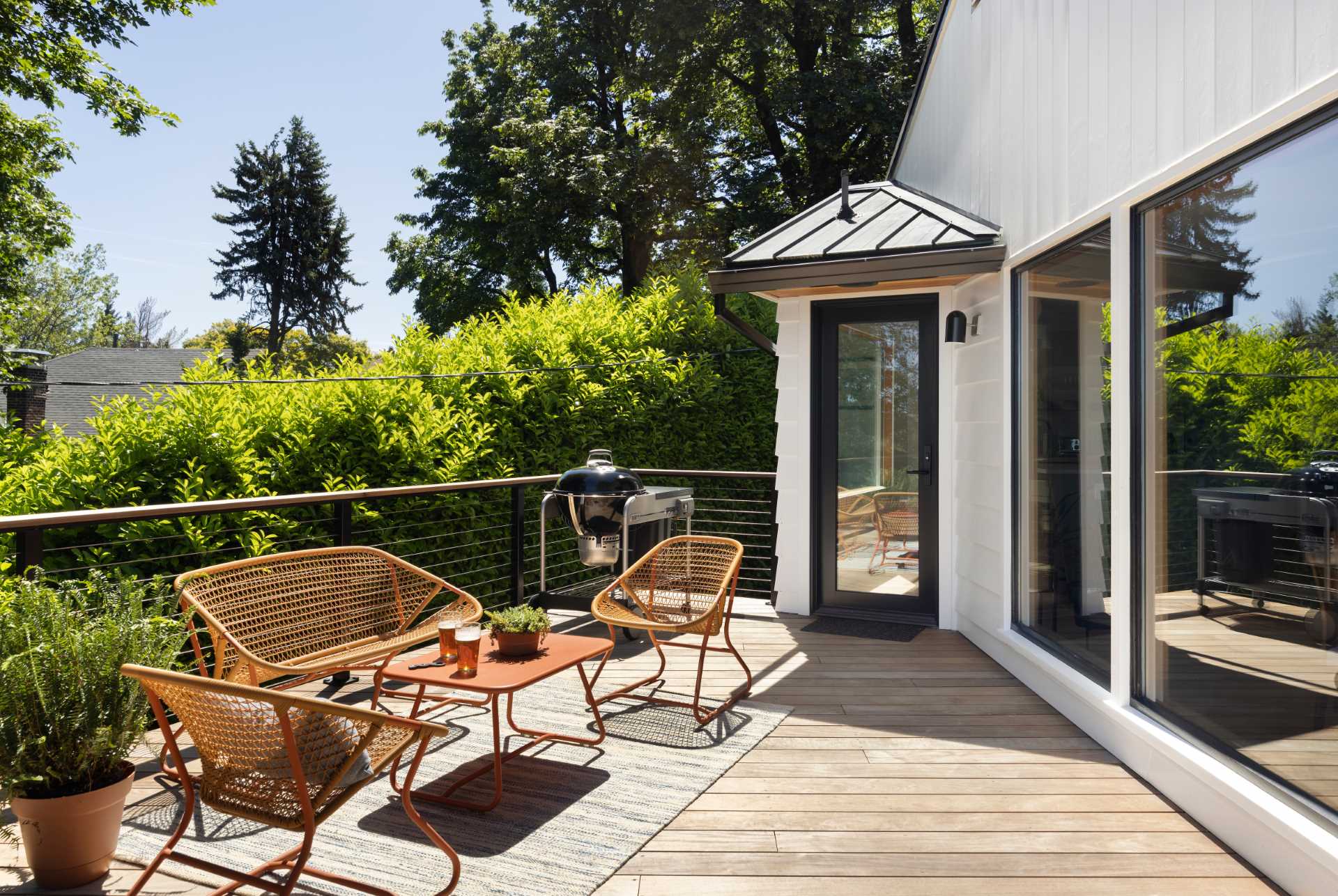 The updated bright white exterior of this home with a metal roof, has black window and door frames. An updated deck extends the living areas of the home.