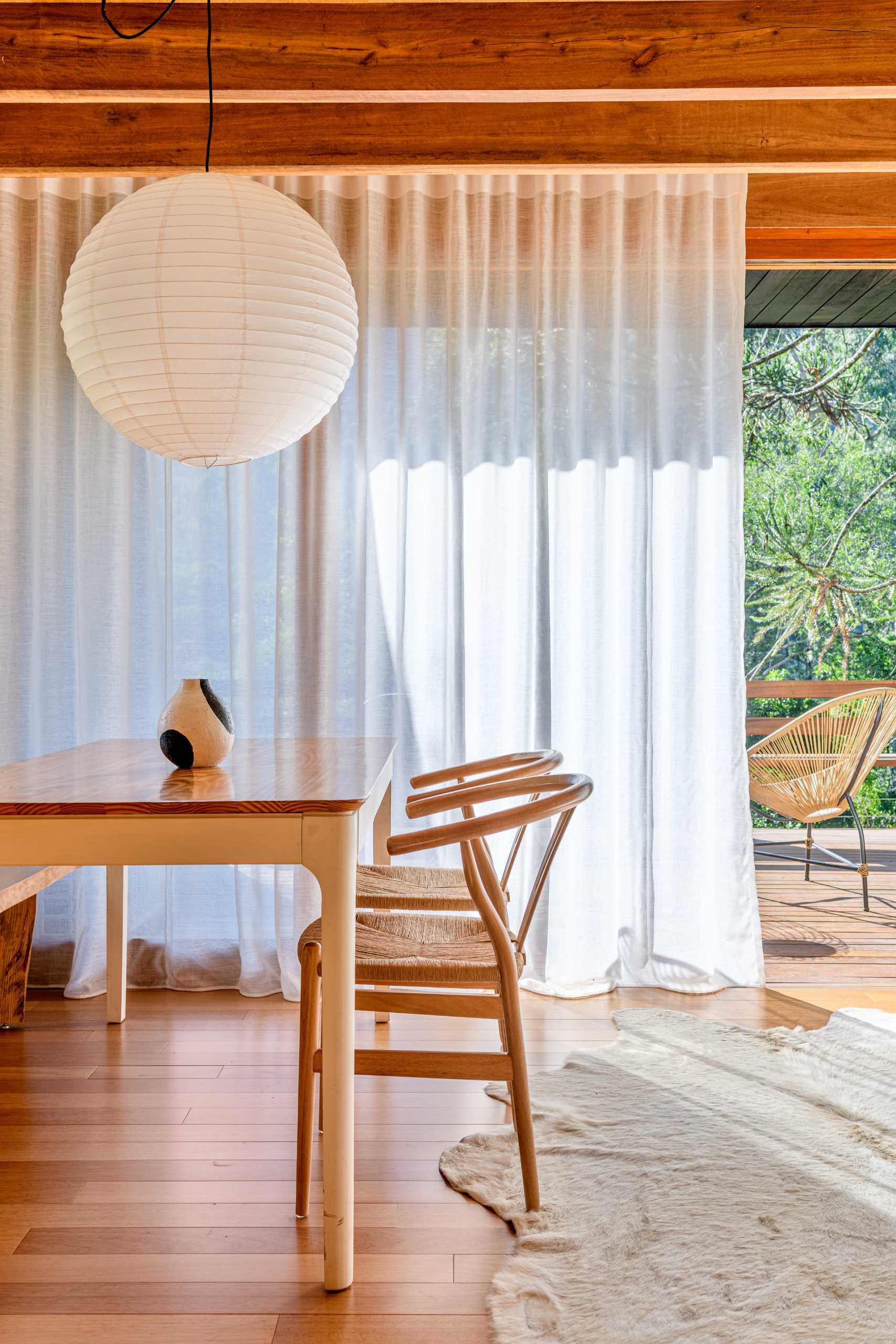 A modern tree house includes a dining area with a table and chairs, and a bench that runs underneath the window to the fireplace.