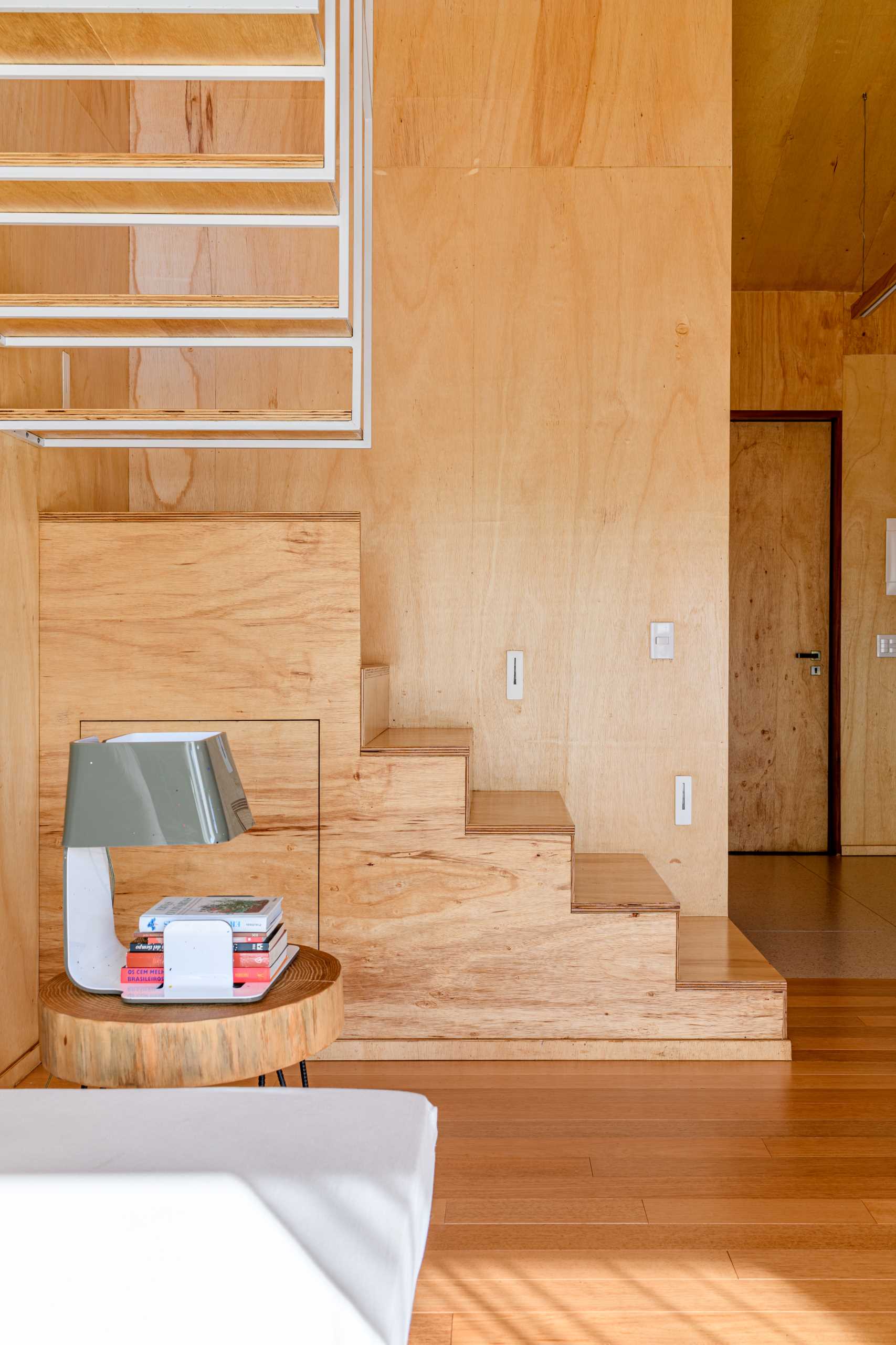 Wood and metal stairs inside a modern tree house with a mezzanine bedroom.