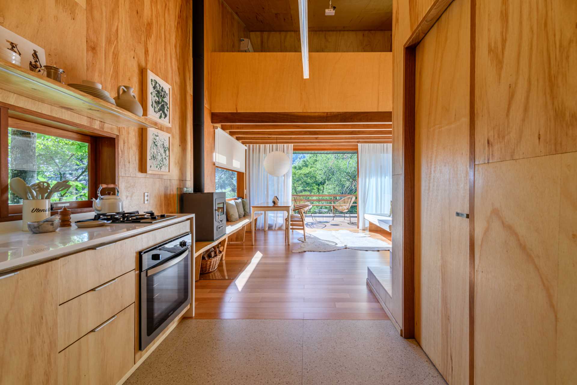 A modern tree house with a living and dining area, a kitchen, a bathroom, and mezzanine bedroom.