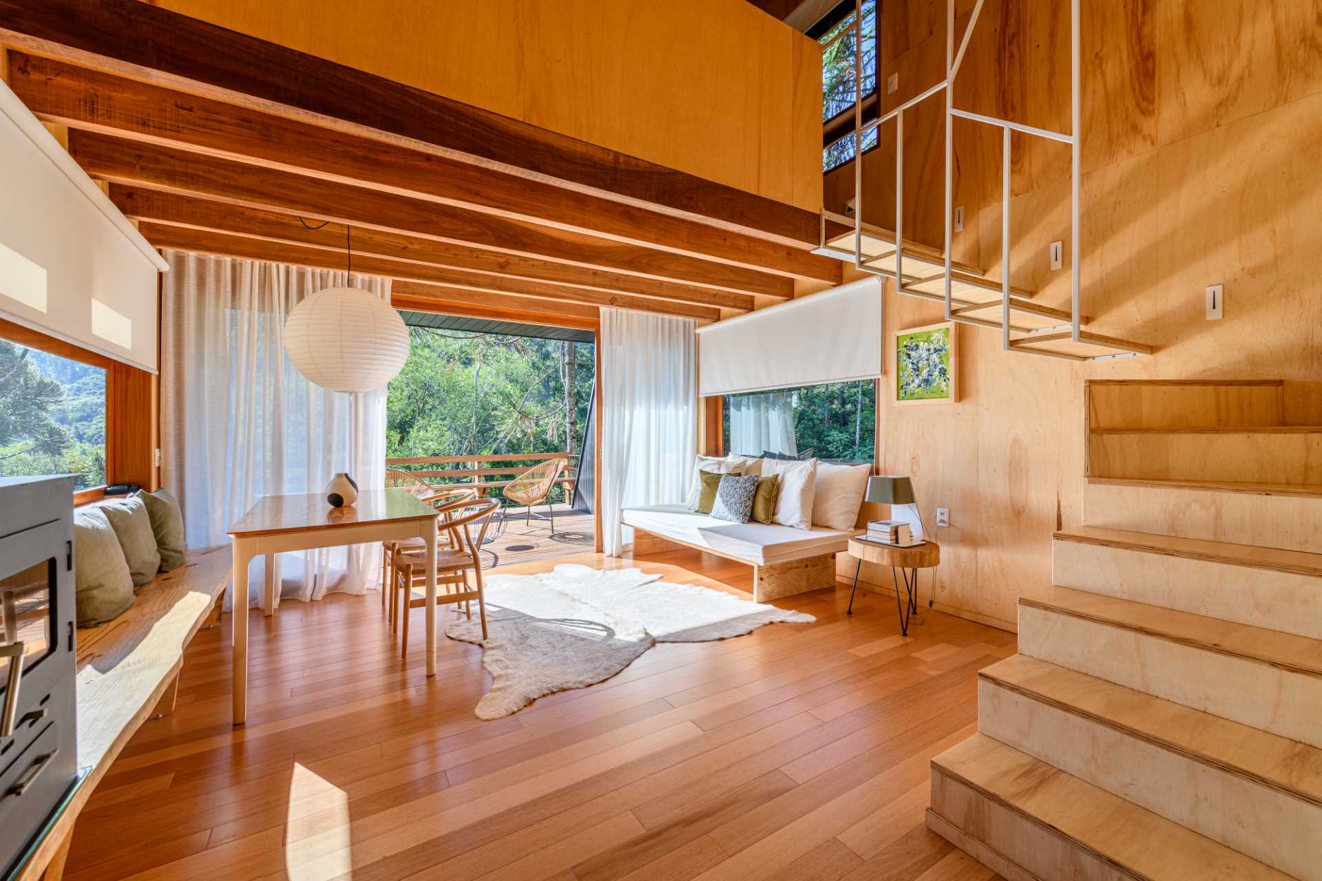 Wood and metal stairs inside a modern tree house with a mezzanine bedroom.