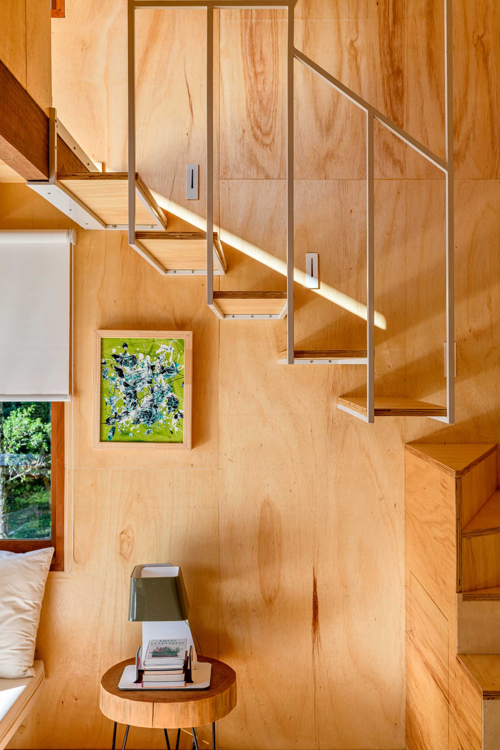 Wood and metal stairs inside a modern tree house with a mezzanine bedroom.