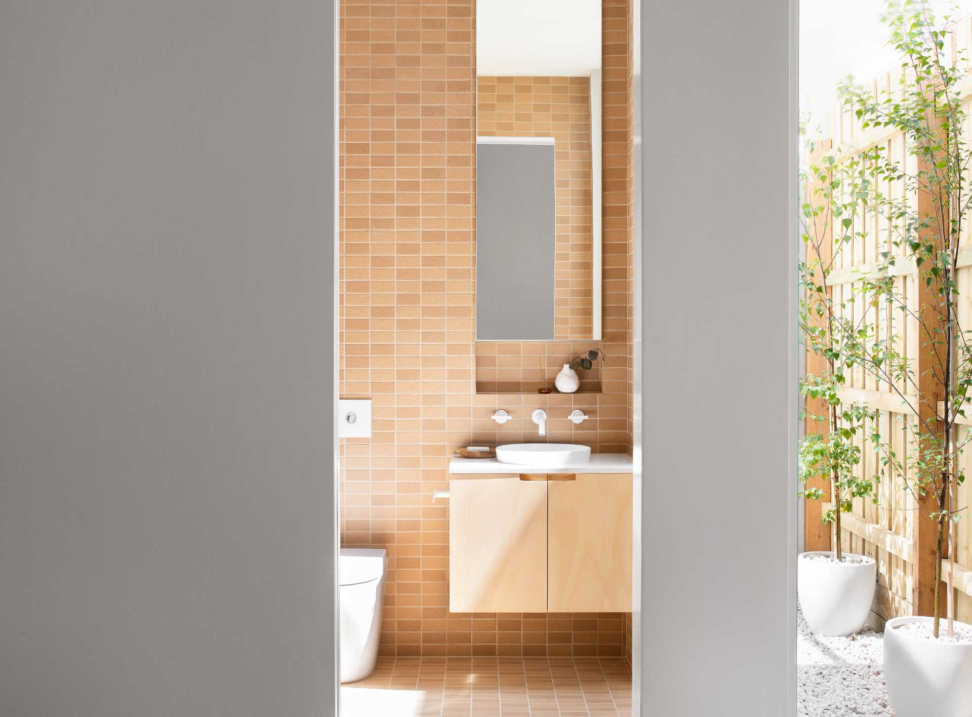 In this modern bathroom, textural Japanese tiles in a terracotta color were chosen to reflect an earthiness, while the crisp white fixtures add freshness, lightness, and a contrasting element.