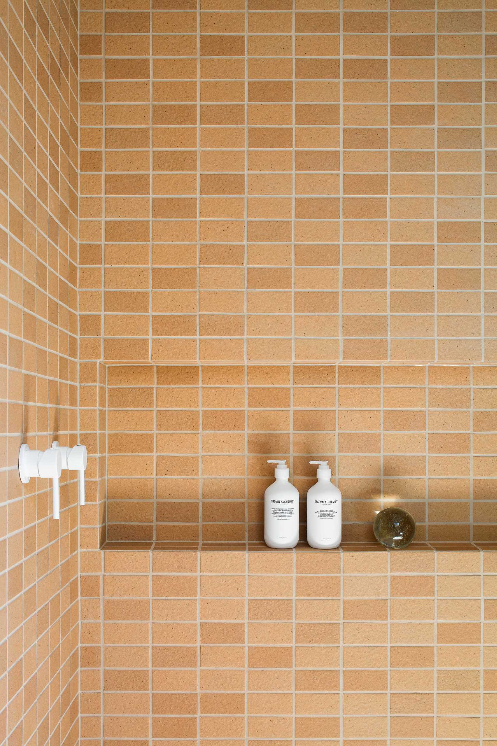 In this modern bathroom, textural Japanese tiles in a terracotta color were chosen to reflect an earthiness, while the crisp white fixtures add freshness, lightness, and a contrasting element.