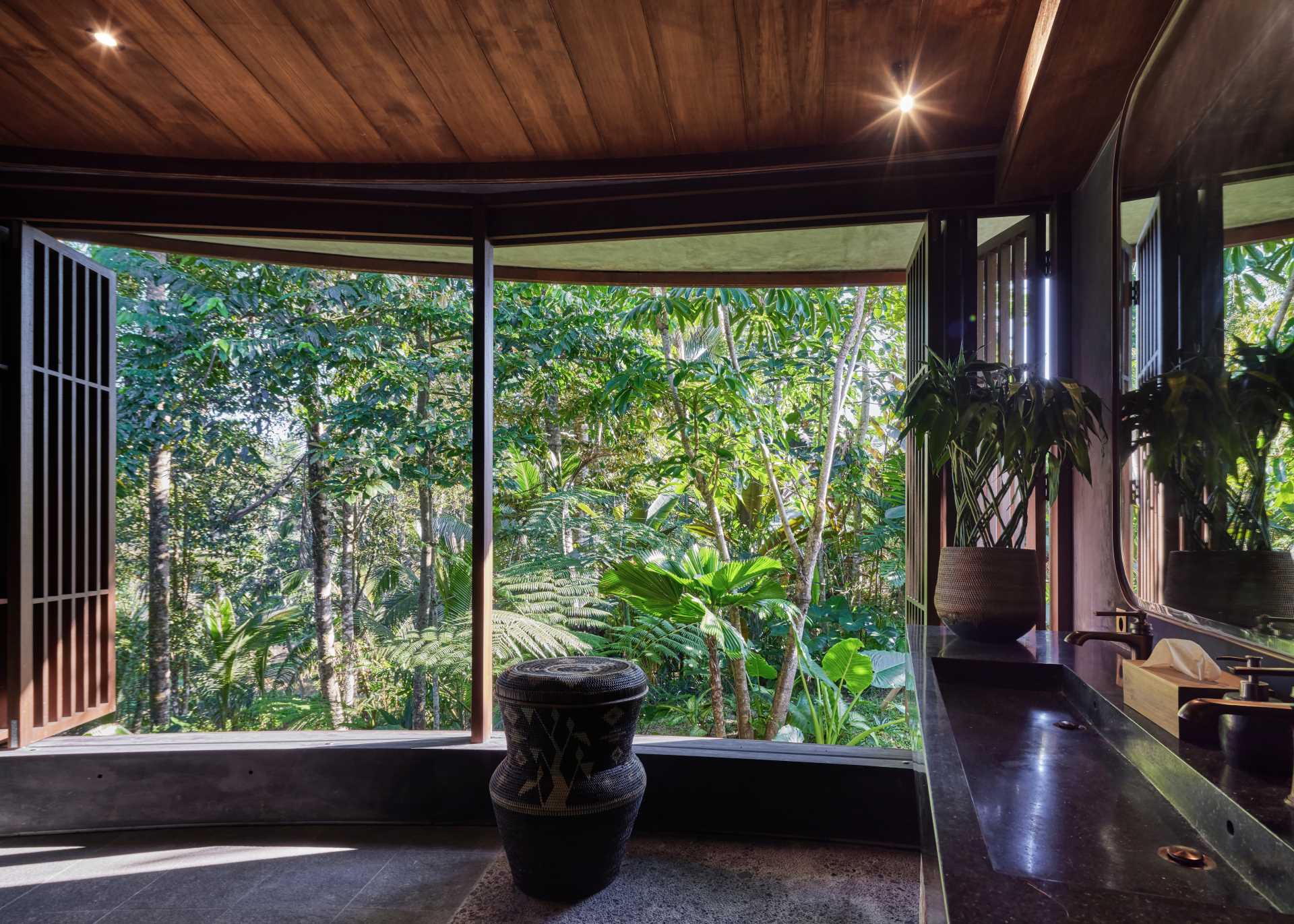 In this bathroom, wood screens open to the jungle, while blue-green tiles line the two-person open shower.