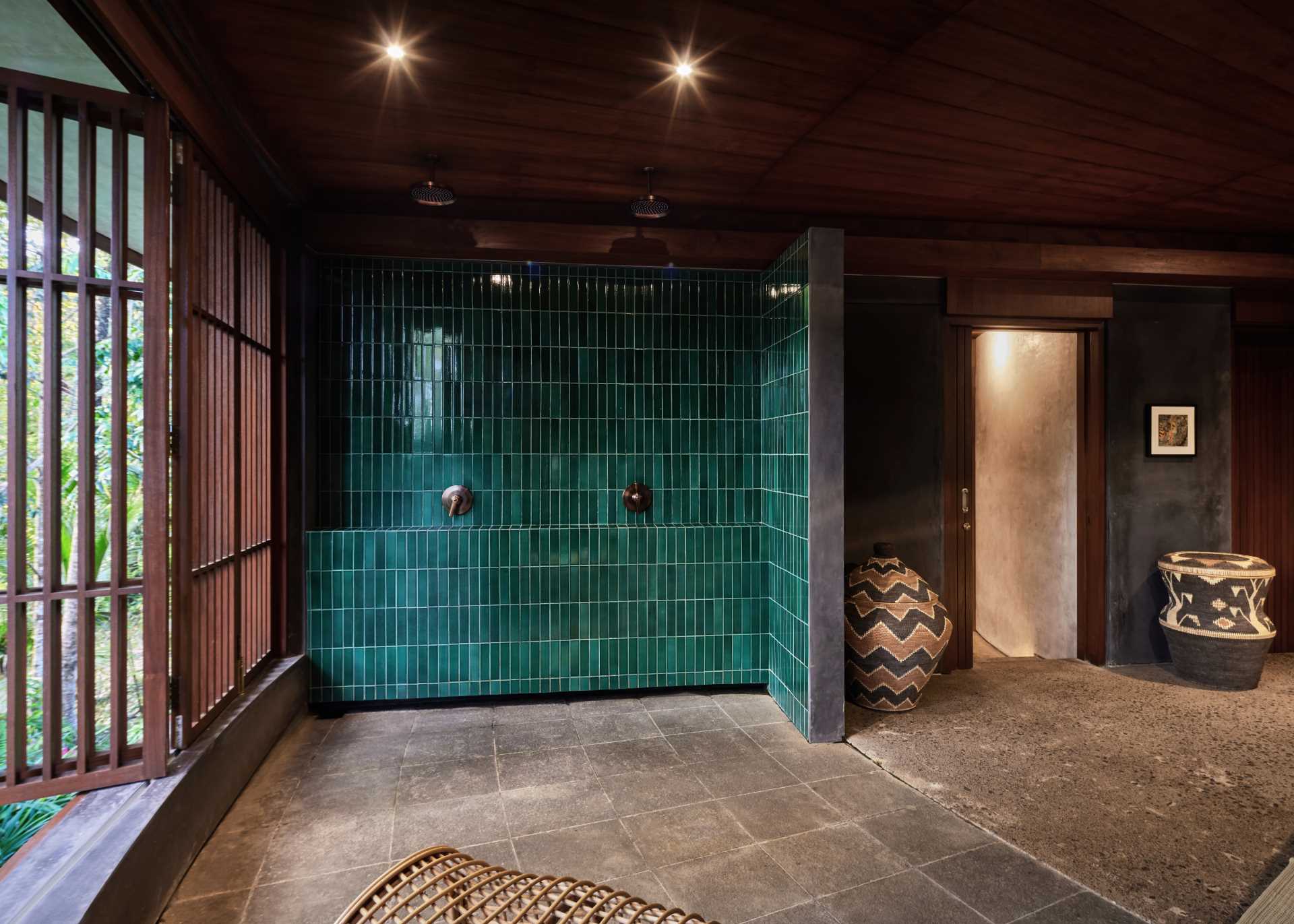 In this bathroom, wood screens open to the jungle, while blue-green tiles line the two-person open shower.