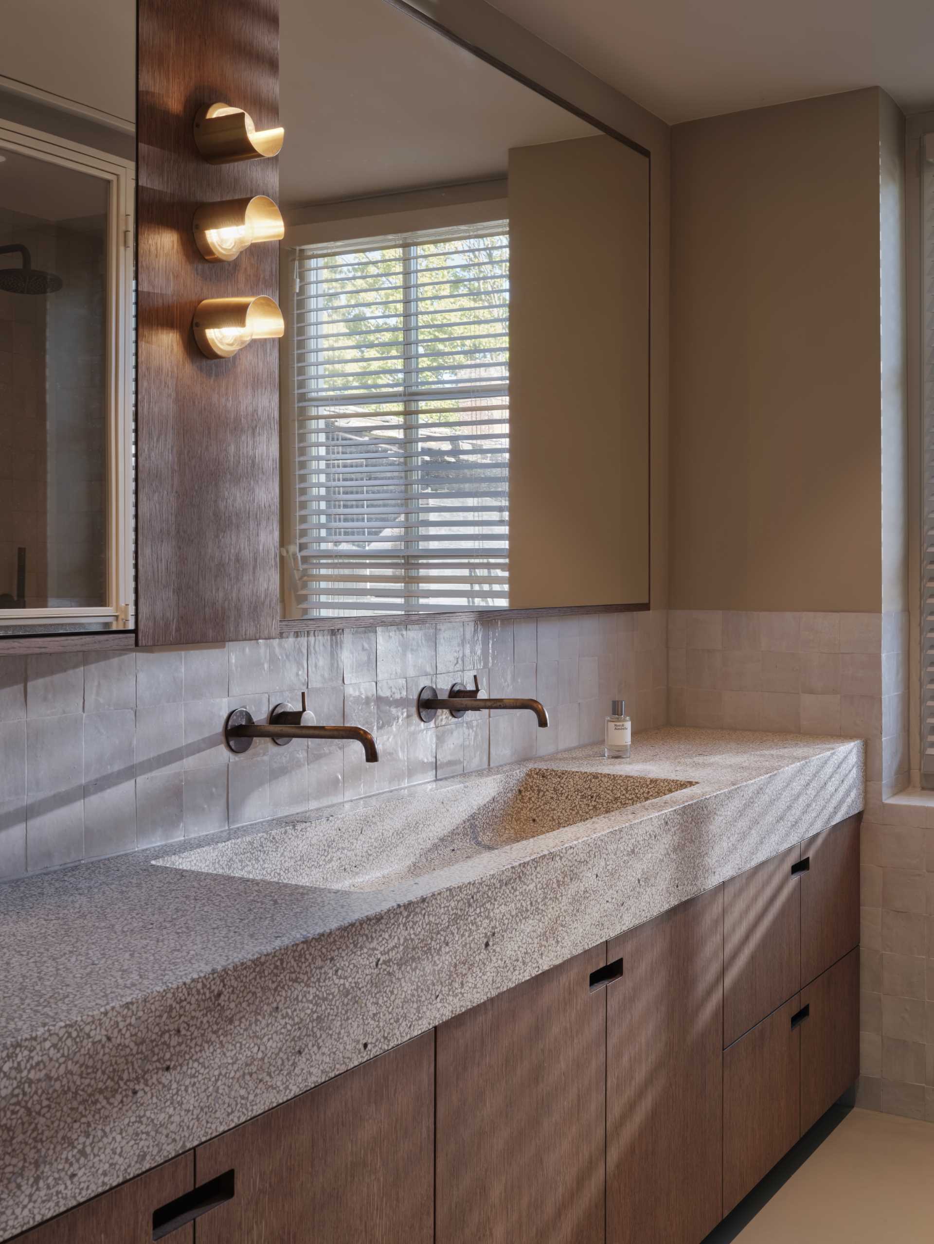 This master bathroom features a  terrazzo blend countertop and sink with green, warm white, and pink pastel marbles that blend nicely with the surrounding colors and wood.