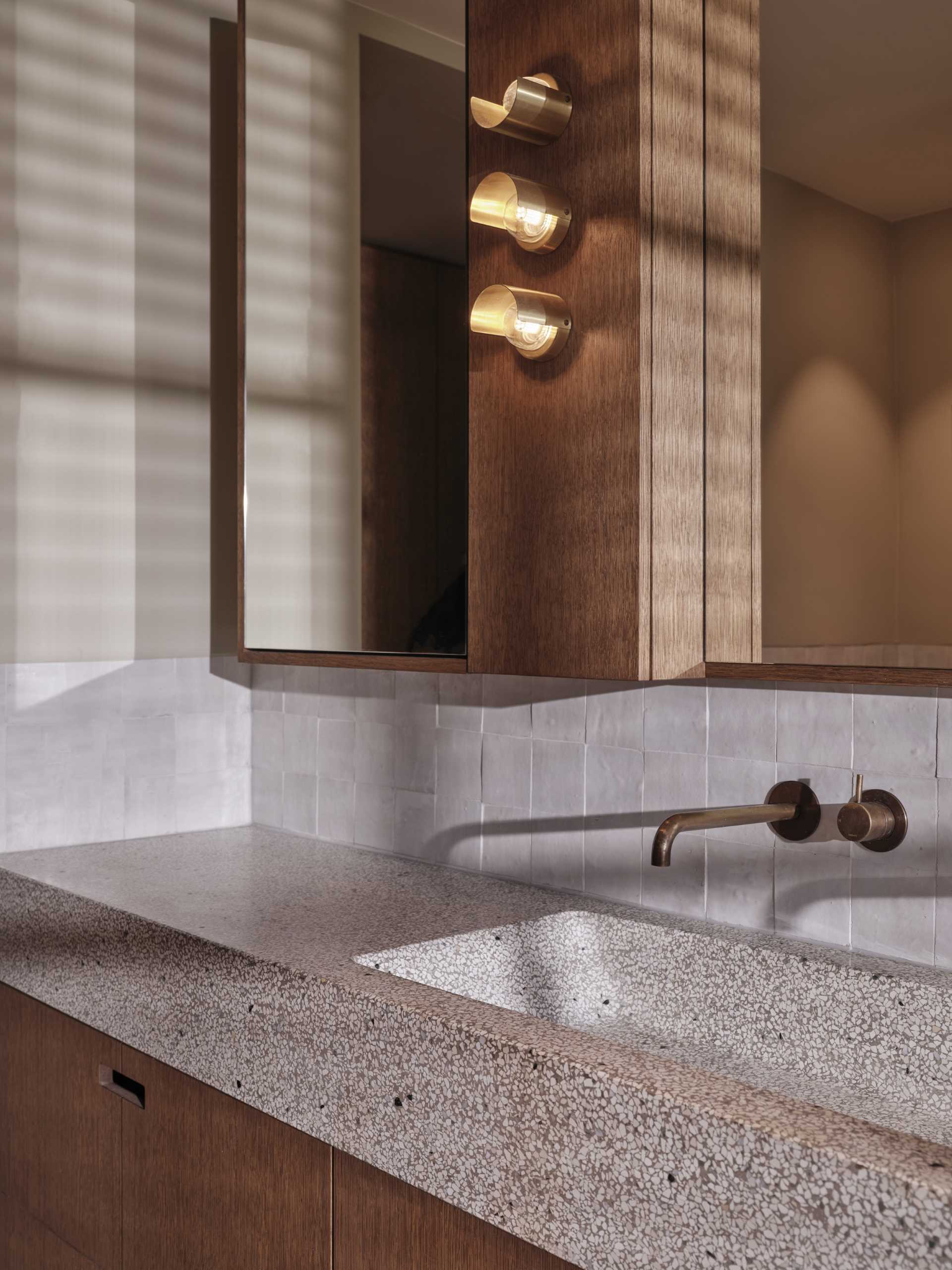 This master bathroom features a  terrazzo blend countertop and sink with green, warm white, and pink pastel marbles that blend nicely with the surrounding colors and wood.