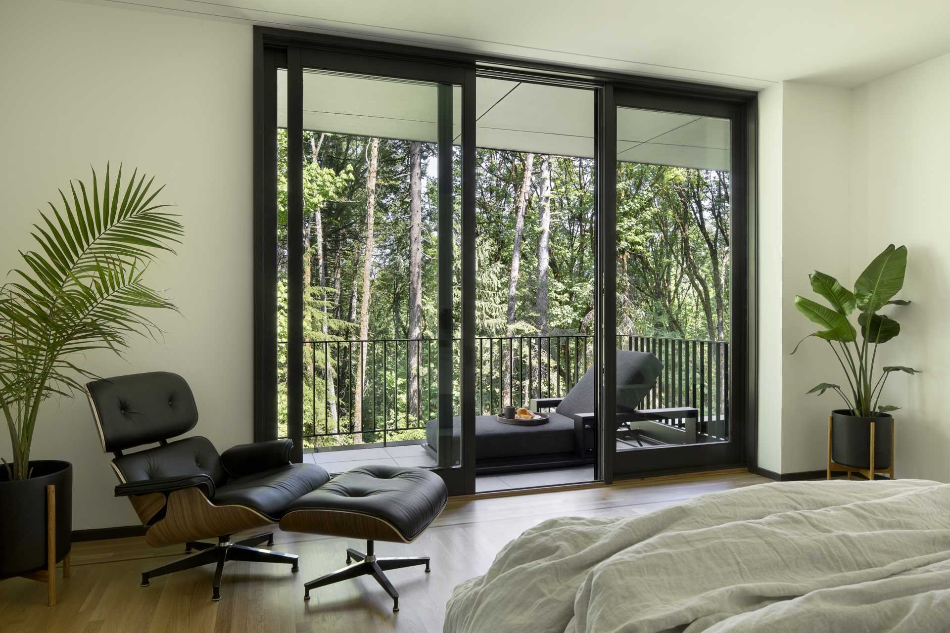 A modern primary bedroom with a sliding glass door that opens up to a private sun deck.