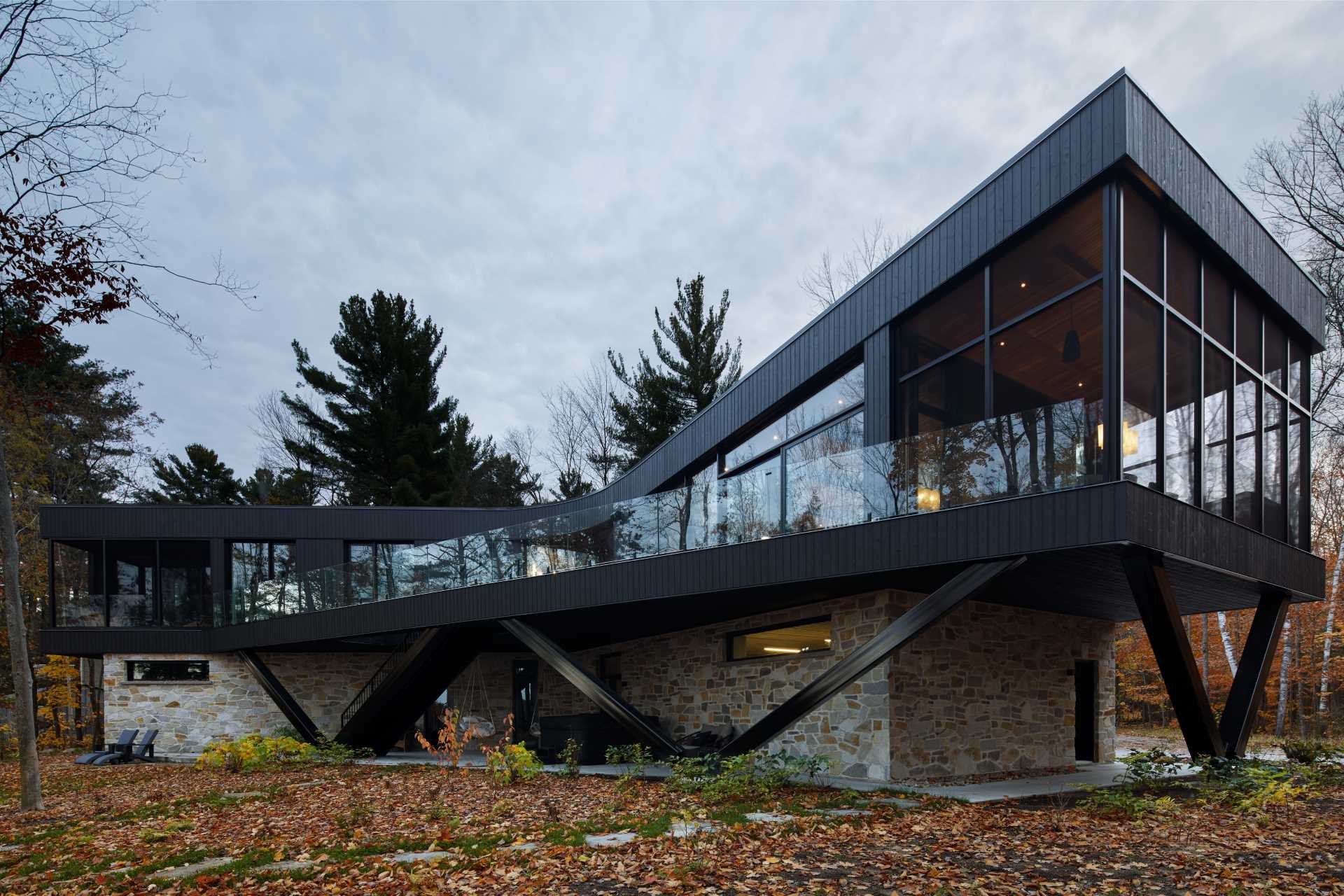 A modern home with a stone foundation and a black upper section.