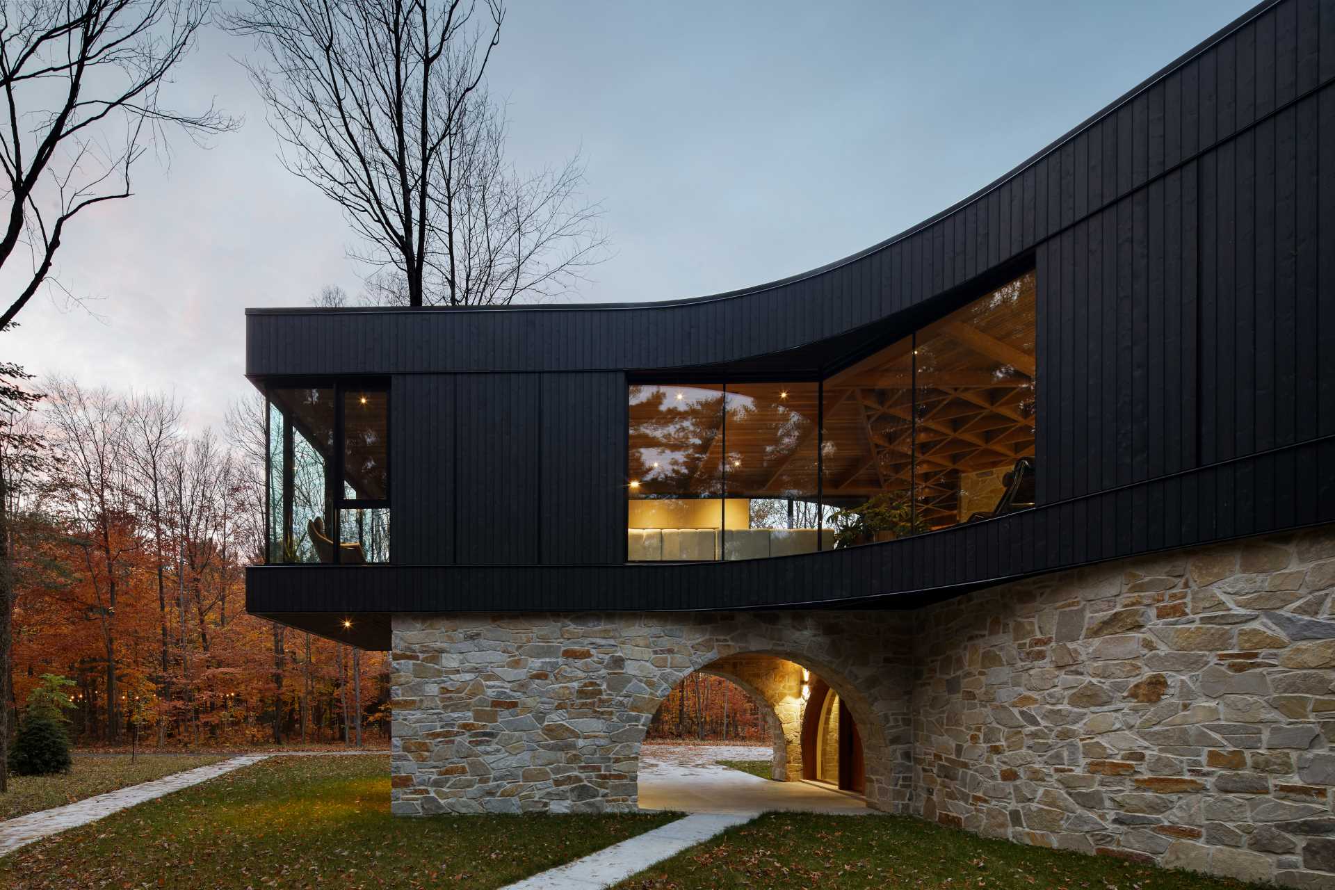 A modern home with a stone foundation and a black upper section.