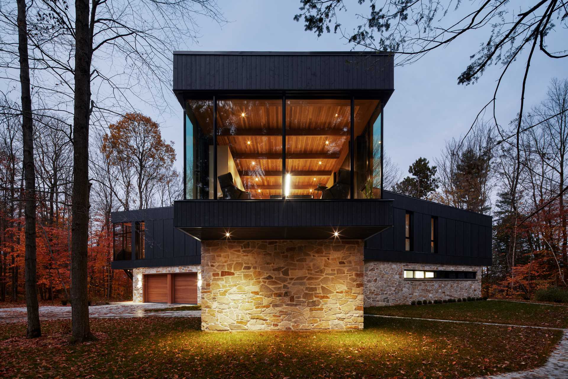 A modern home with a stone foundation and a black upper section.