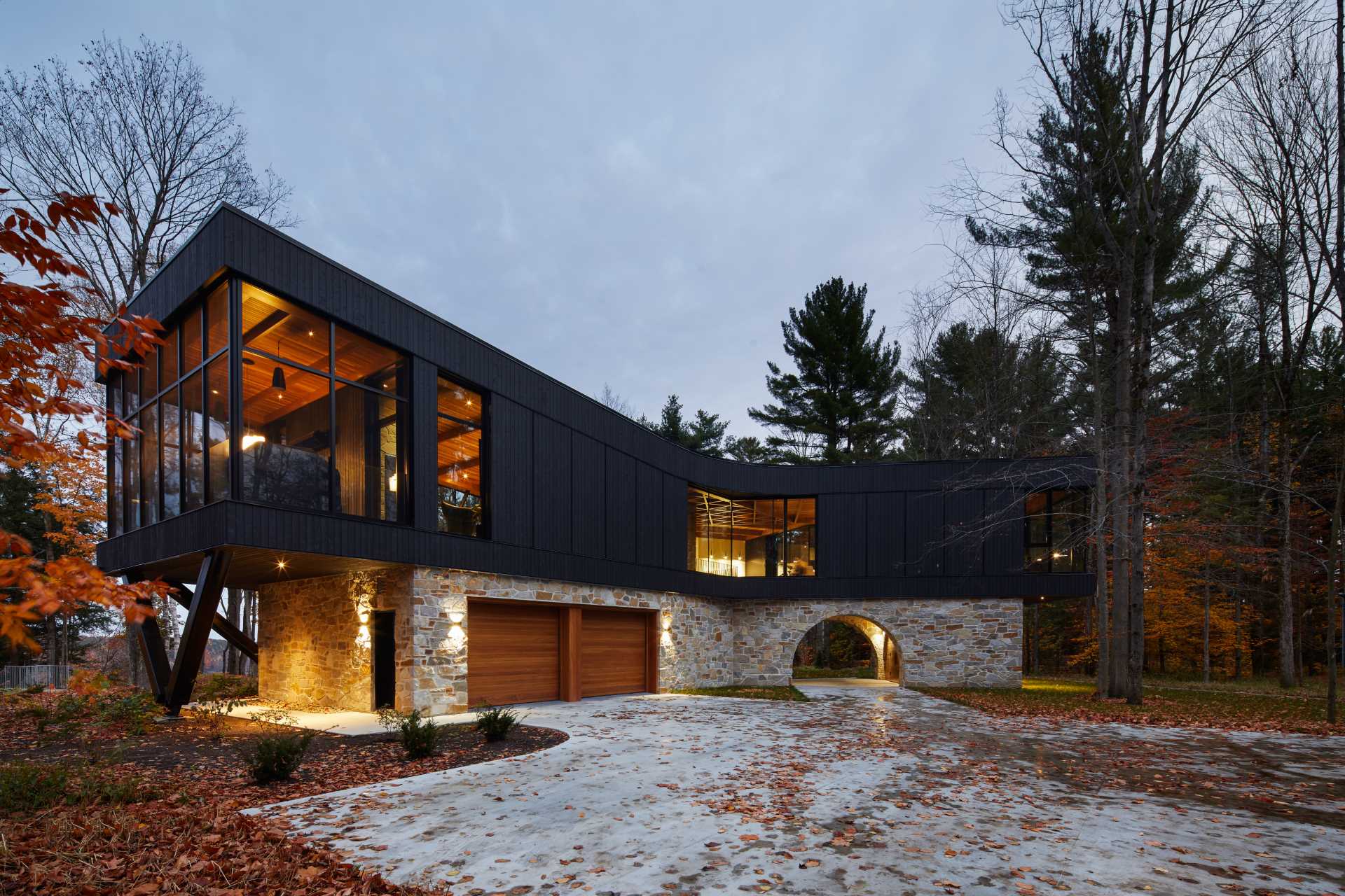 A modern home with a stone foundation and a black upper section.