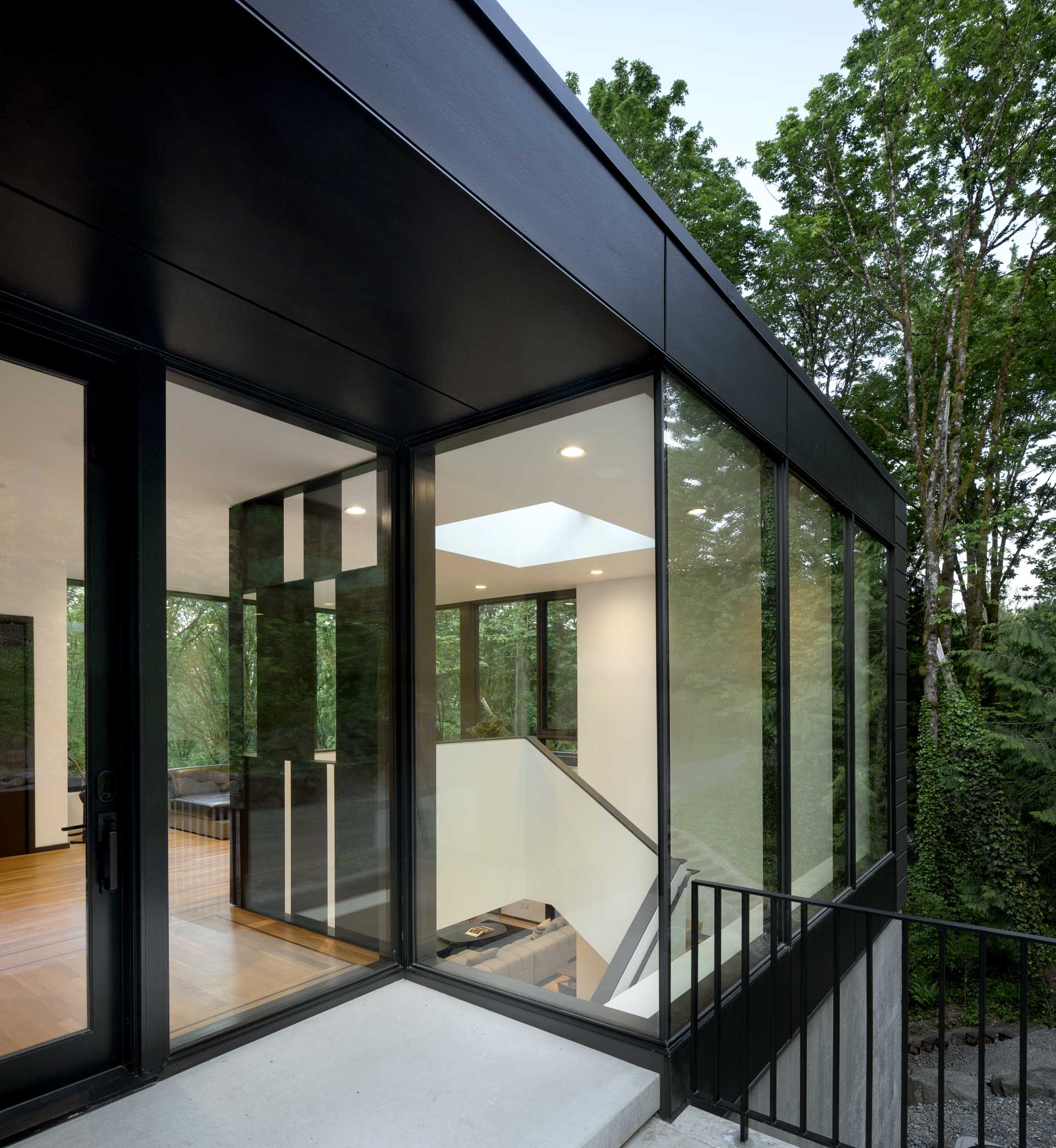 A modern black house with floor-to-ceiling windows and glass front door.