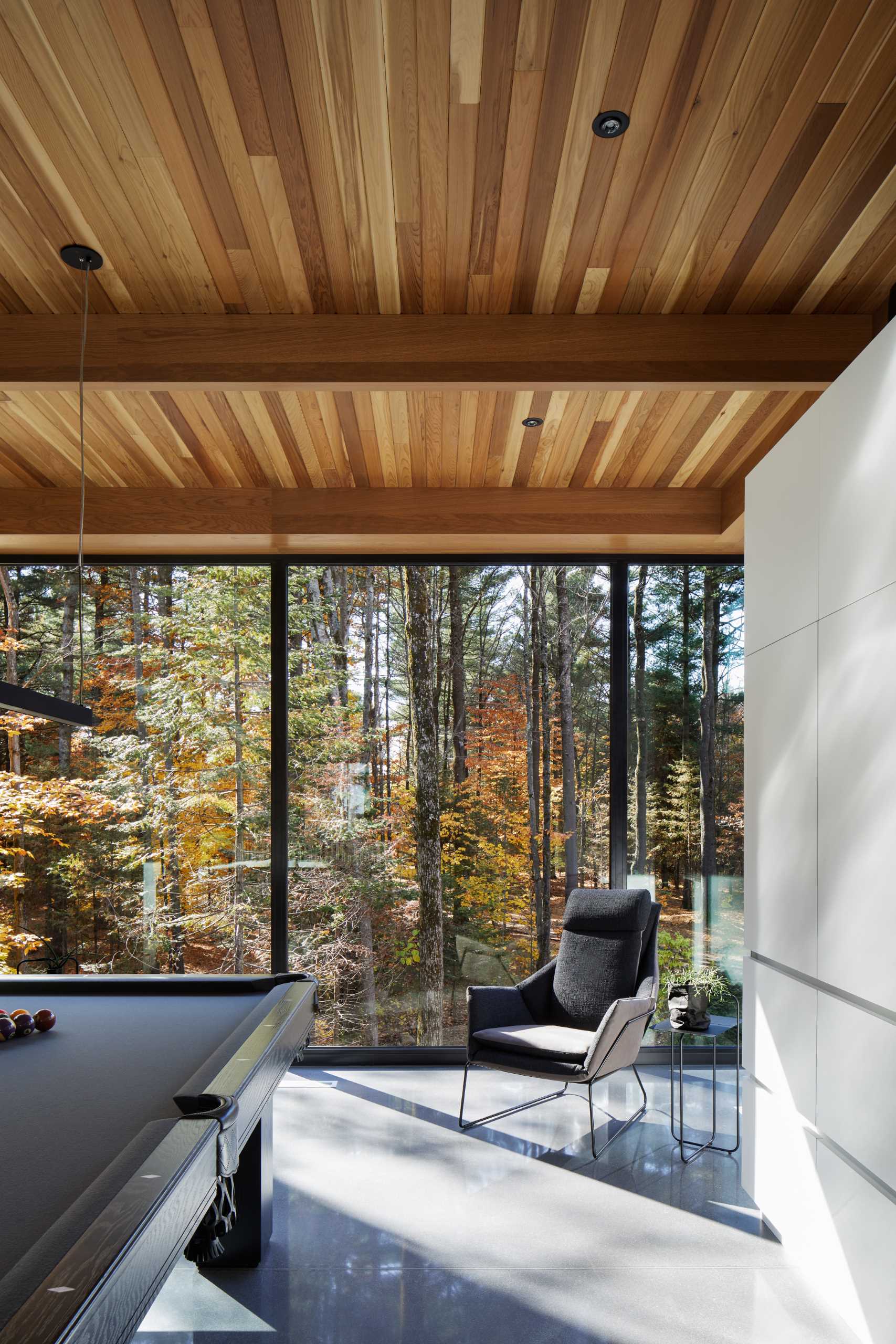 A secondary living room with a large couch and games area is filled with natural light from the floor-to-ceiling windows.