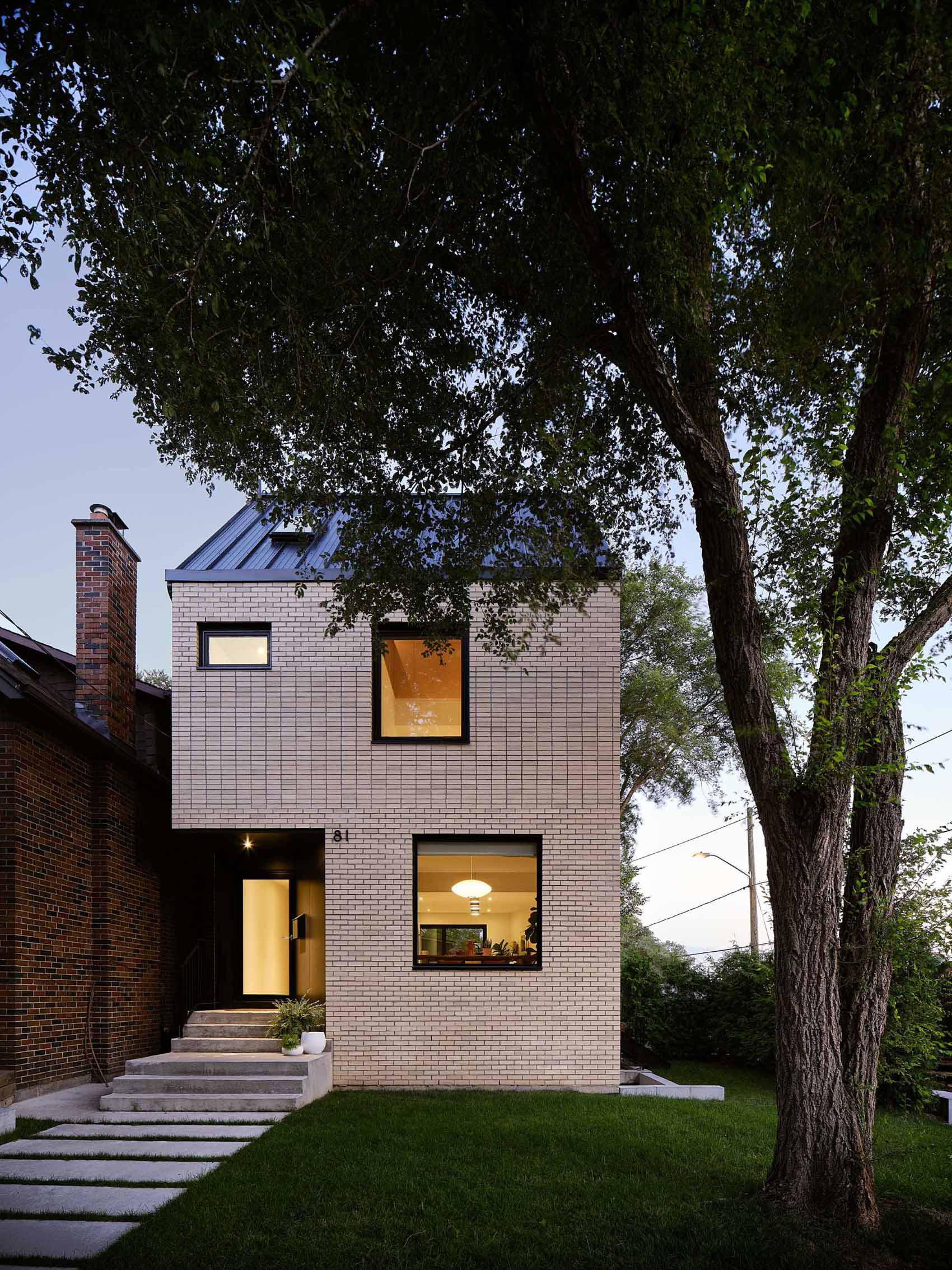 The exterior of this modern home is clad in old historical buff yellow brick in varying banded coursing patterns that feature across the facades.