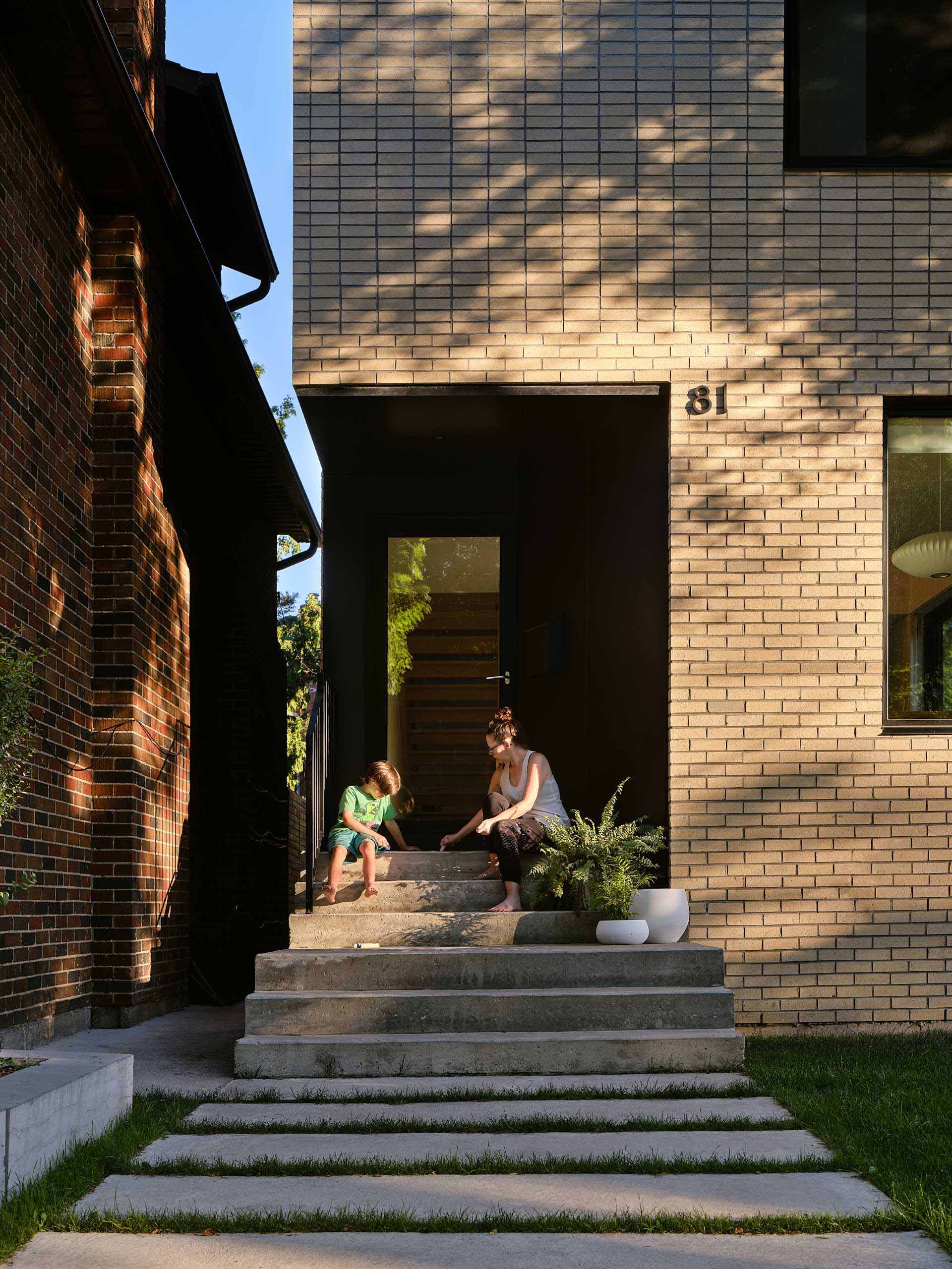 The front entry and third-floor deck of this modern home are carved from brick with contrasting black sintered stone panels.