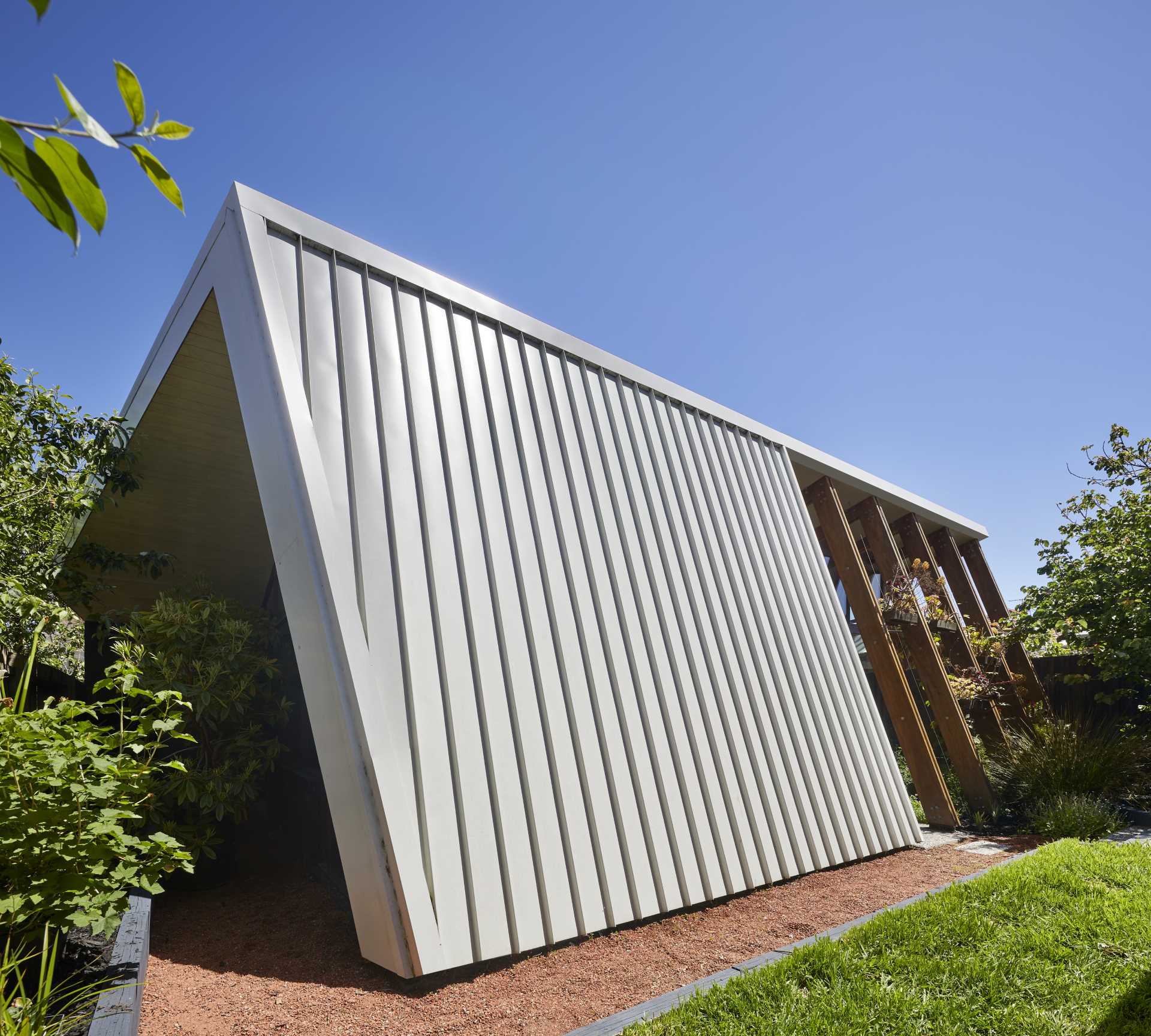 The arbor-like structure of this home addition includes shelving and wire guides that over time, will allow the plants to grow, providing shade and privacy for the interior.