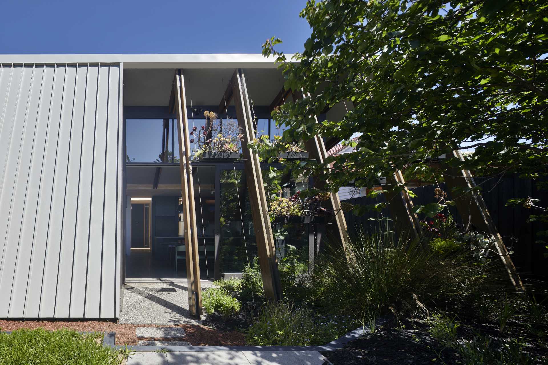 The arbor-like structure of this home addition includes shelving and wire guides that over time, will allow the plants to grow, providing shade and privacy for the interior.