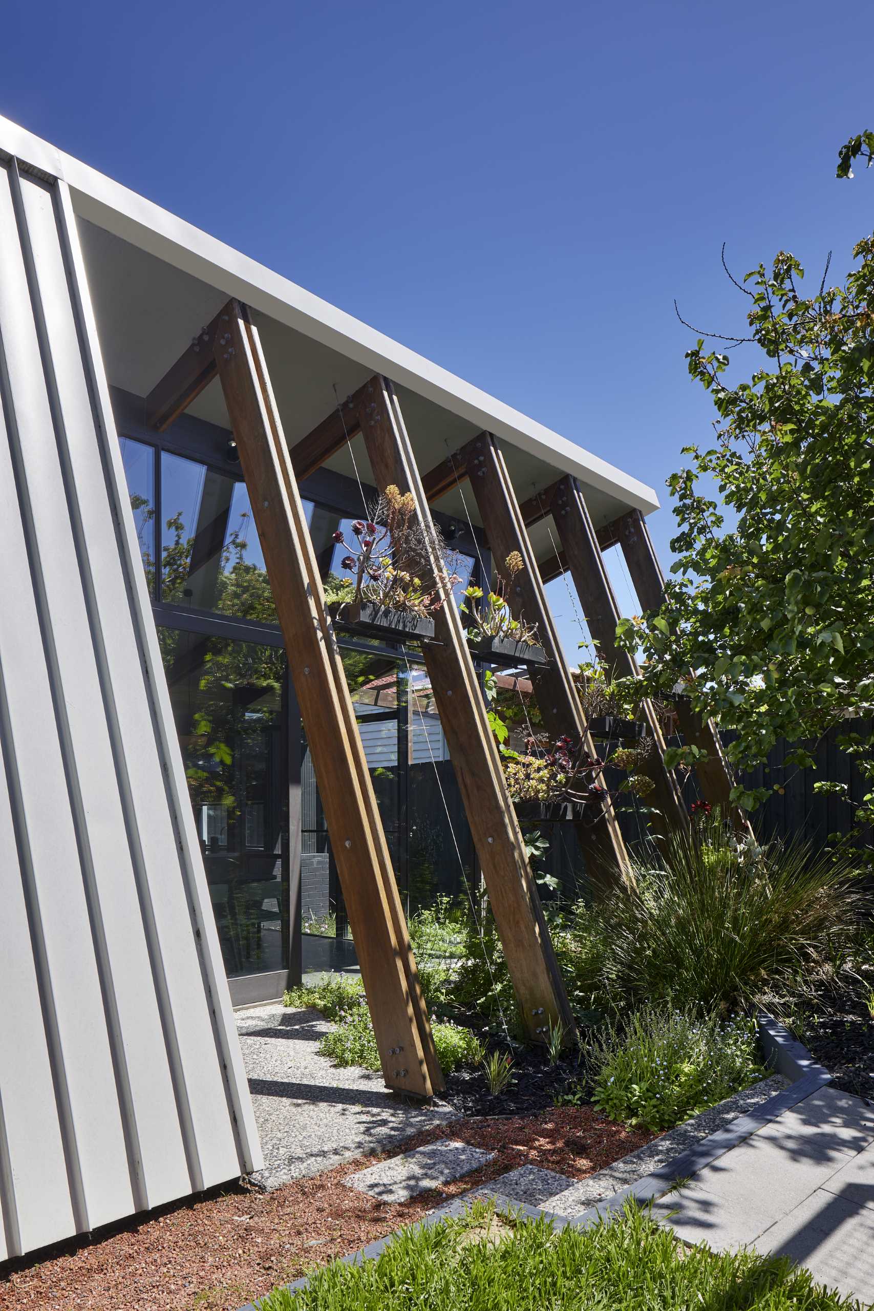 The arbor-like structure of this home addition includes shelving and wire guides that over time, will allow the plants to grow, providing shade and privacy for the interior.