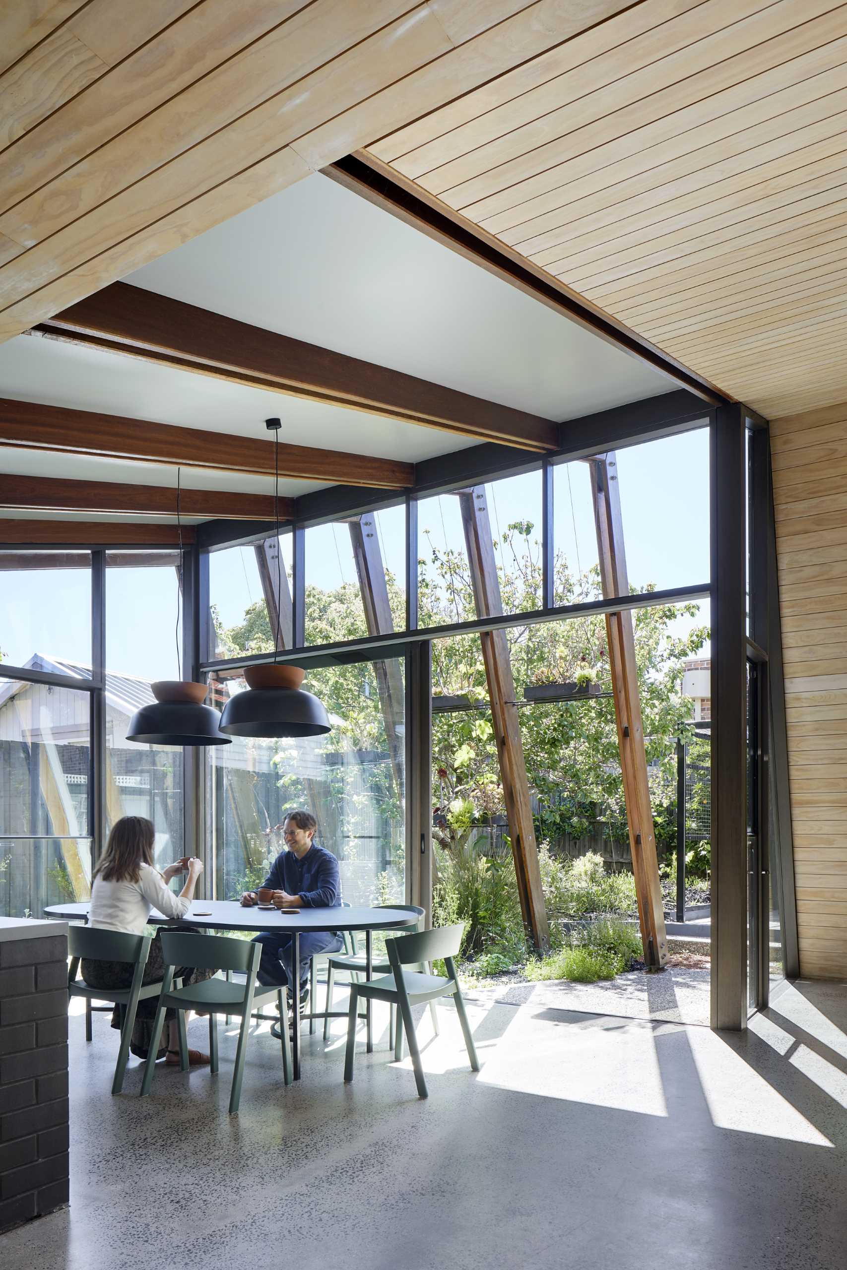 The walls of this rear home extension dissolve thanks to floor-to-ceiling sliding glass doors filling the interior with natural light. 