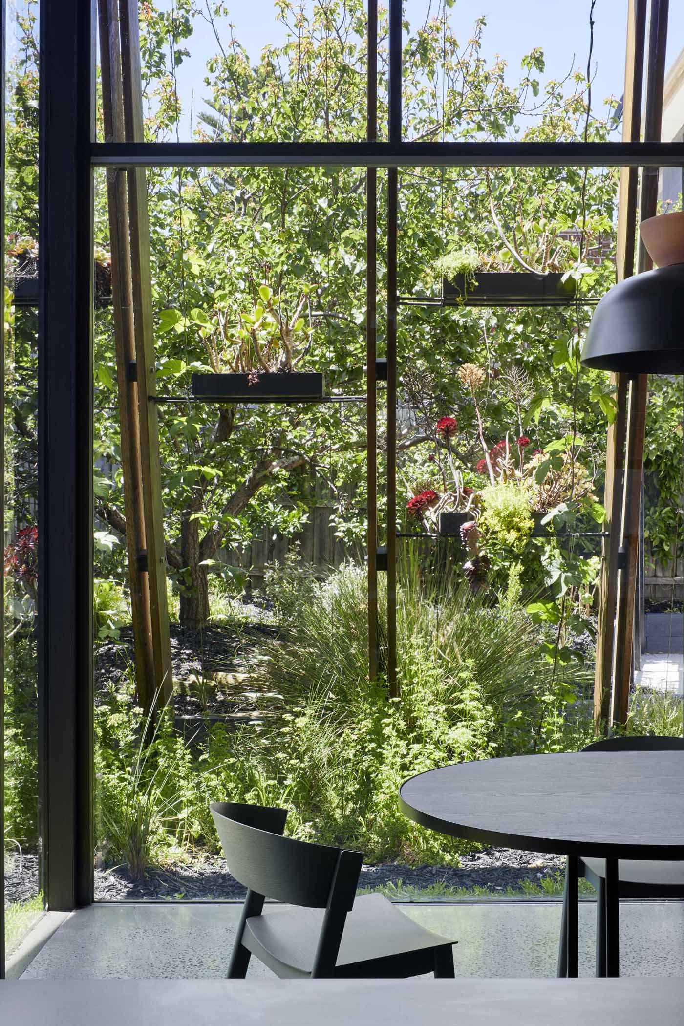 The walls of this rear home extension dissolve thanks to floor-to-ceiling sliding glass doors filling the interior with natural light. 