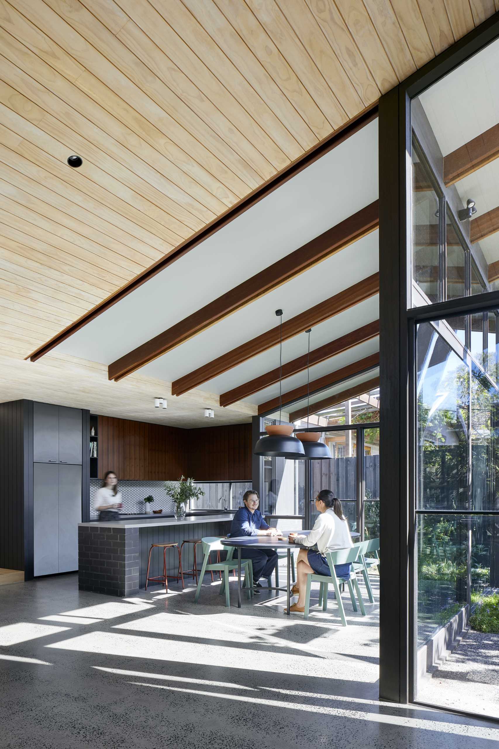 The dining area and kitchen are finished in greys, charcoals, and dusty greens, creating the perfect backdrop to offset and complement the garden's lush green.