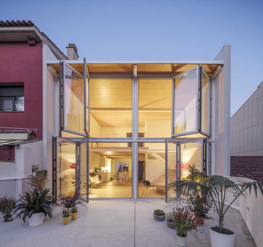 A modern home with a wall of foldable windows that connect the interior with the courtyard outside.