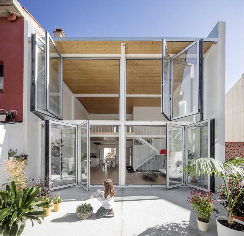 A modern home with a wall of foldable windows that connect the interior with the courtyard outside.