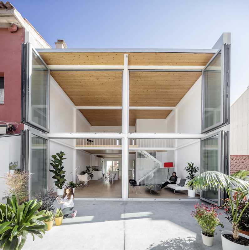 A modern home with a wall of foldable windows that connect the interior with the courtyard outside.