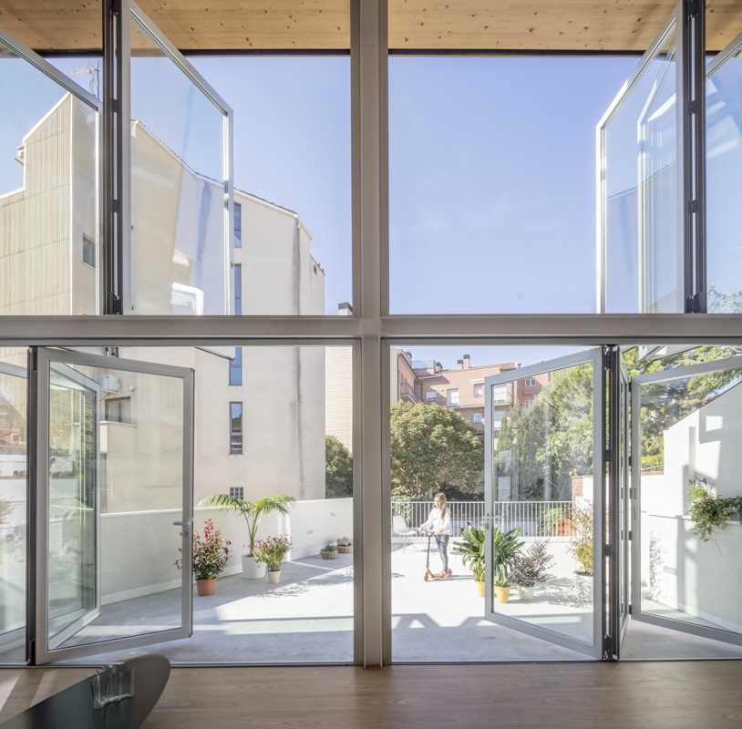 A modern home with a wall of foldable windows that connect the interior with the courtyard outside.